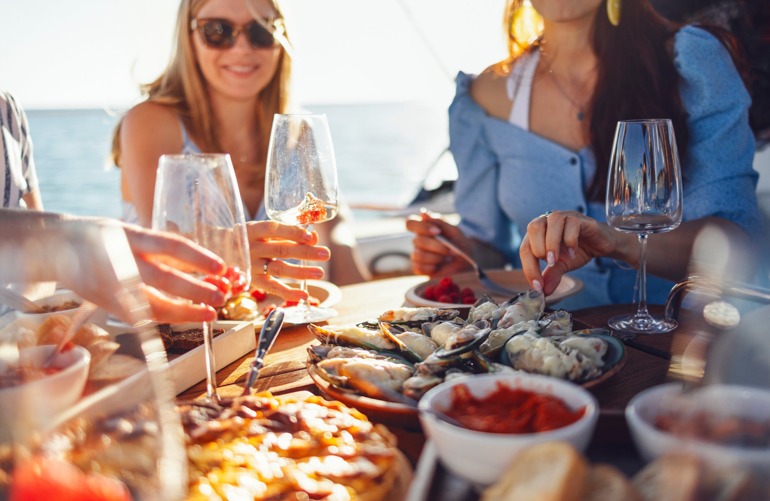 People enjoying a seafood dinner outdoors on a boat with the ocean in the background.