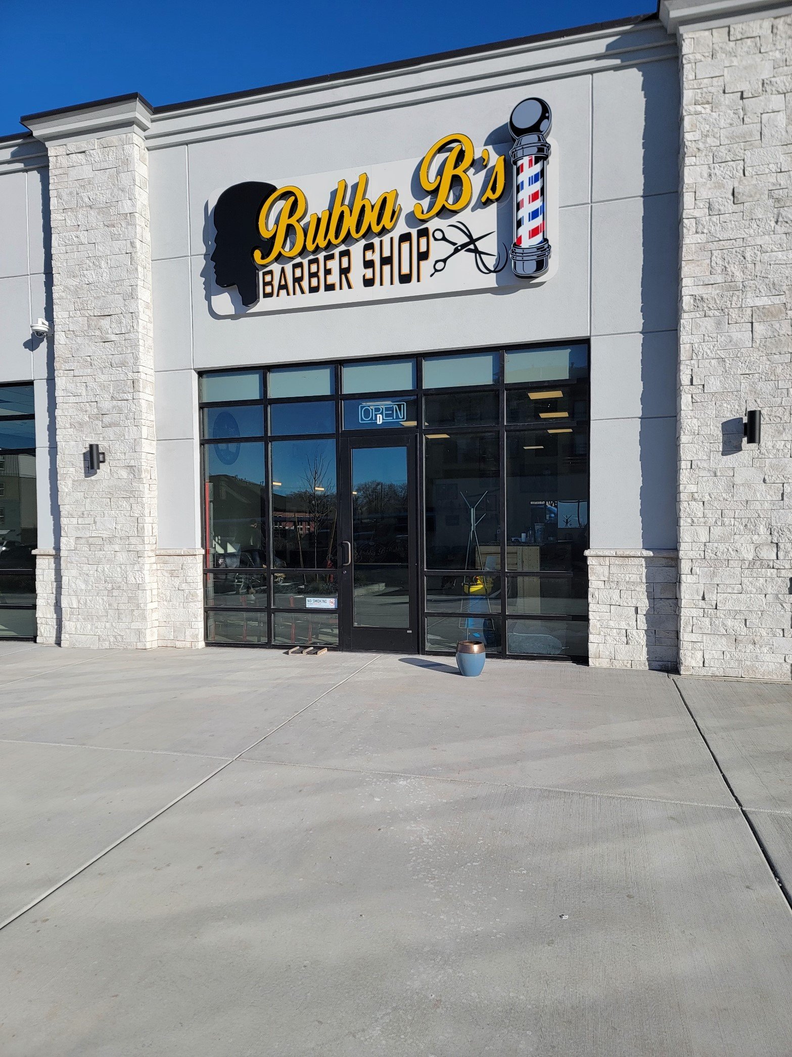 Exterior of Bubba B's Barber Shop with sign and barber pole.