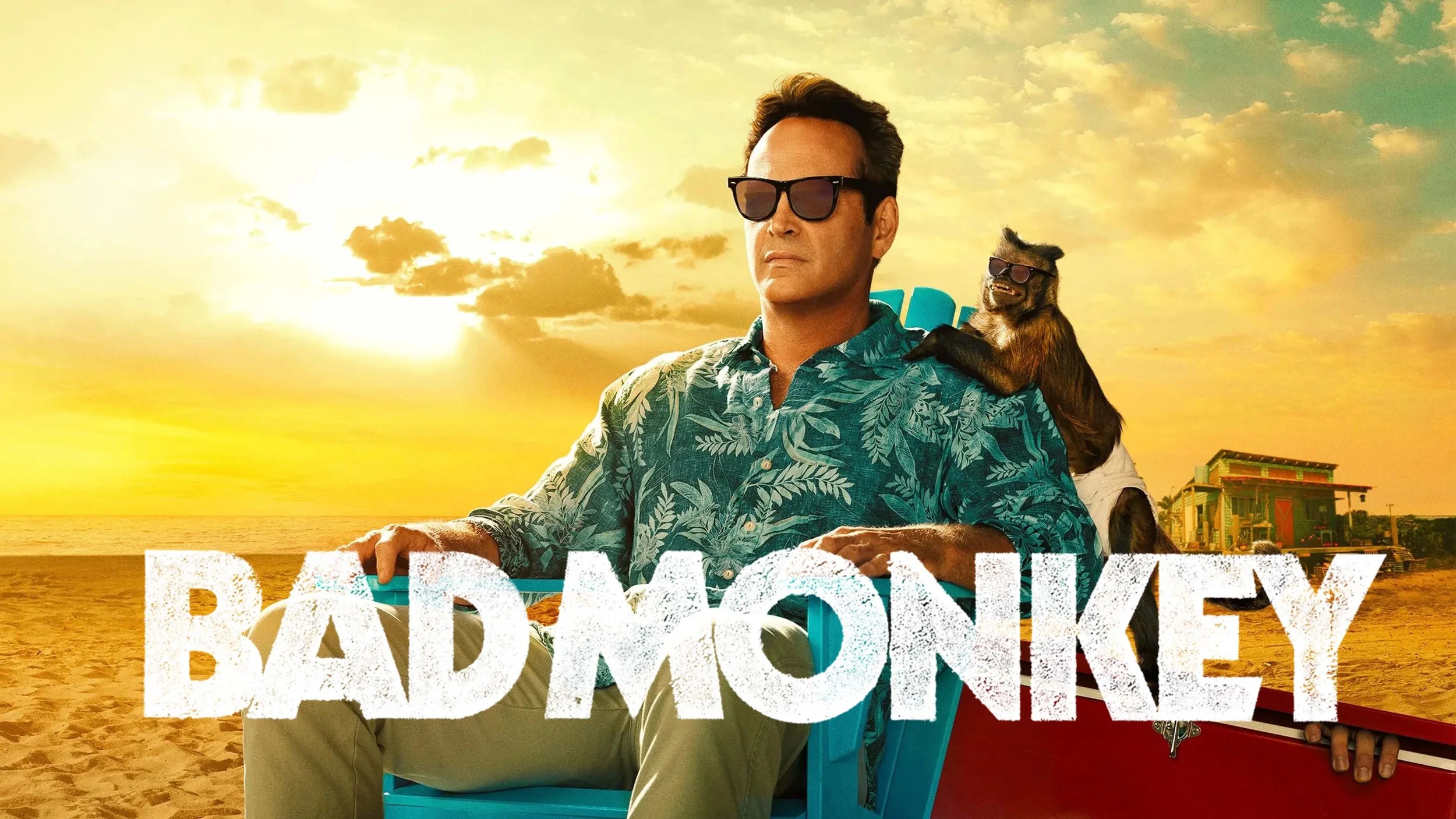 A man in sunglasses in a Hawaiian shirt sitting on a beach chair at sunset, with a monkey on his shoulder also wearing sunglasses, and the words "Bad Monkey" in large white letters across the image.