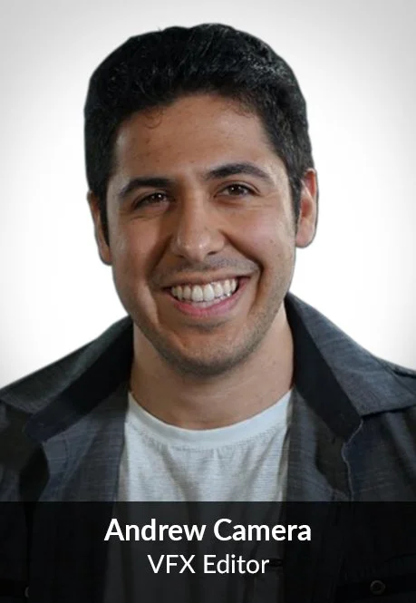 A smiling man with dark hair wearing a dark jacket and light shirt in front of a plain light background.