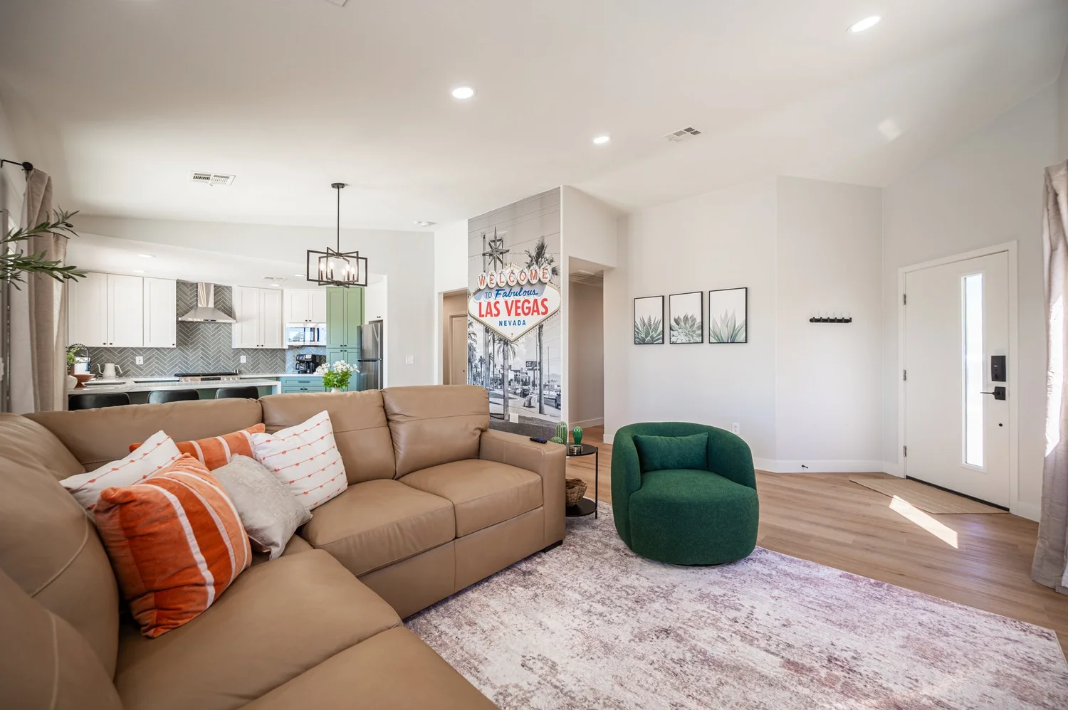 Living room in the Las Vegas Airbnb with a brown sectional sofa, green velvet swivel chair and orange accent pillows