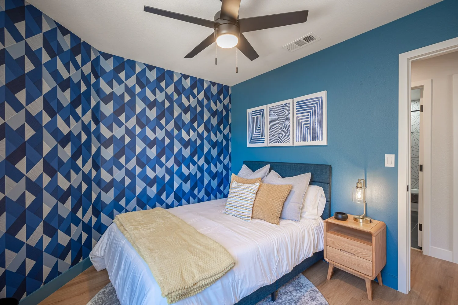 Blue bedroom in the Las Vegas Airbnb with geometric blue wallpaper, a full bed and yellow accents