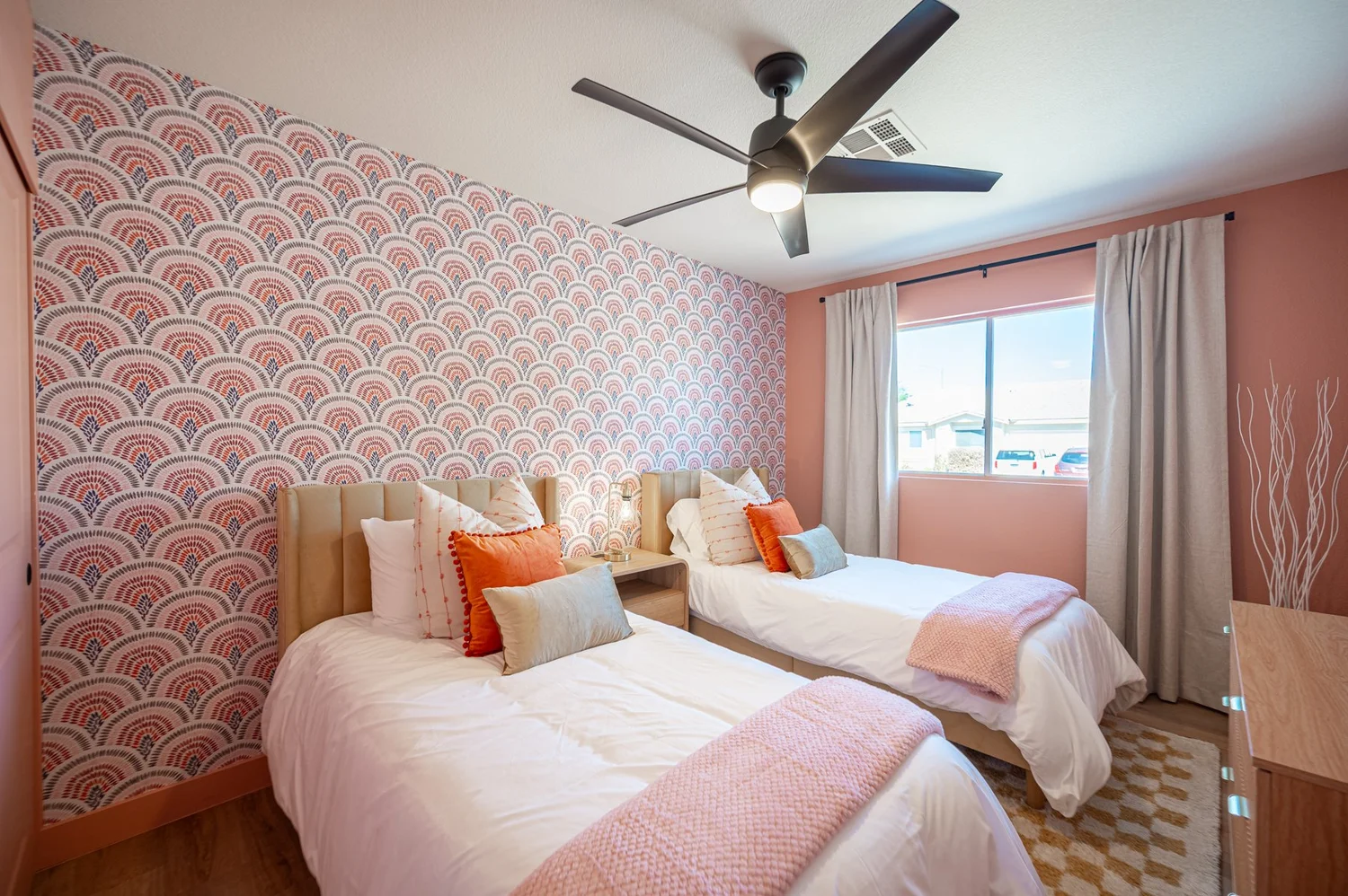 Flamingo pink bedroom in the Las Vegas Airbnb with two twin beds, patterned wallpaper and orange accents