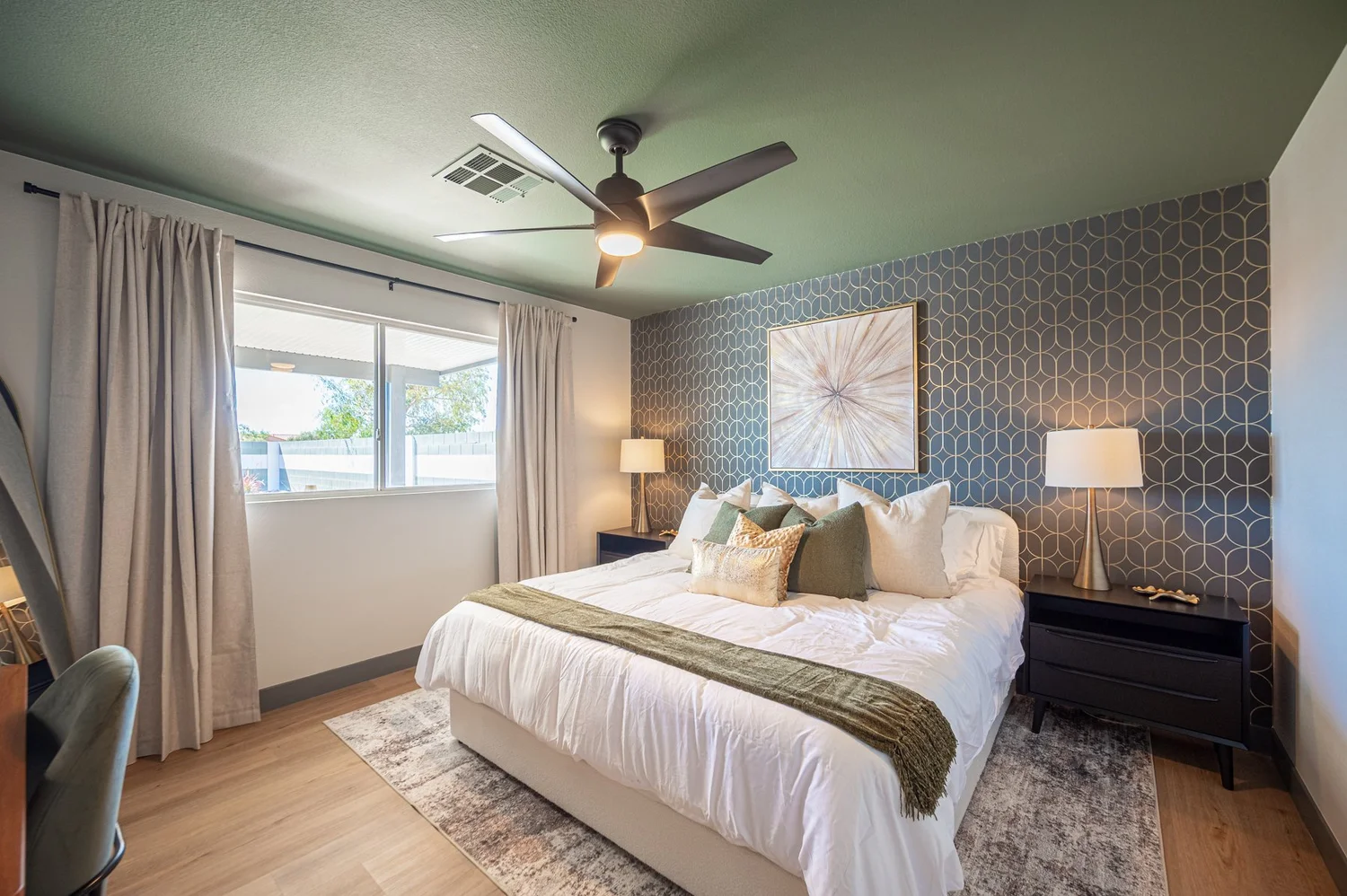 Master bedroom in the Las Vegas Airbnb with a green ceiling, upholstered king bed and work desk