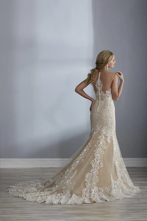 A woman in a white lace wedding dress standing sideways in a minimalist room.
