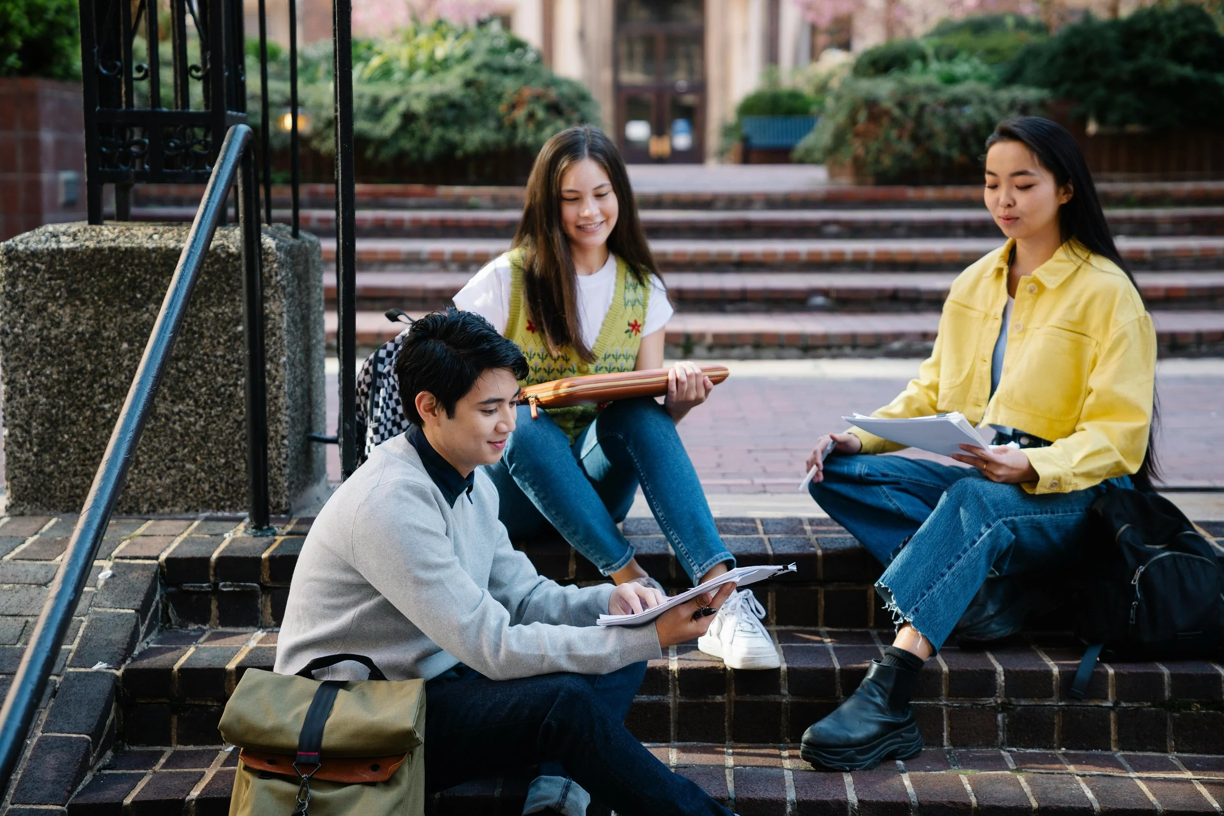 Three students sitting on steps and talking outside