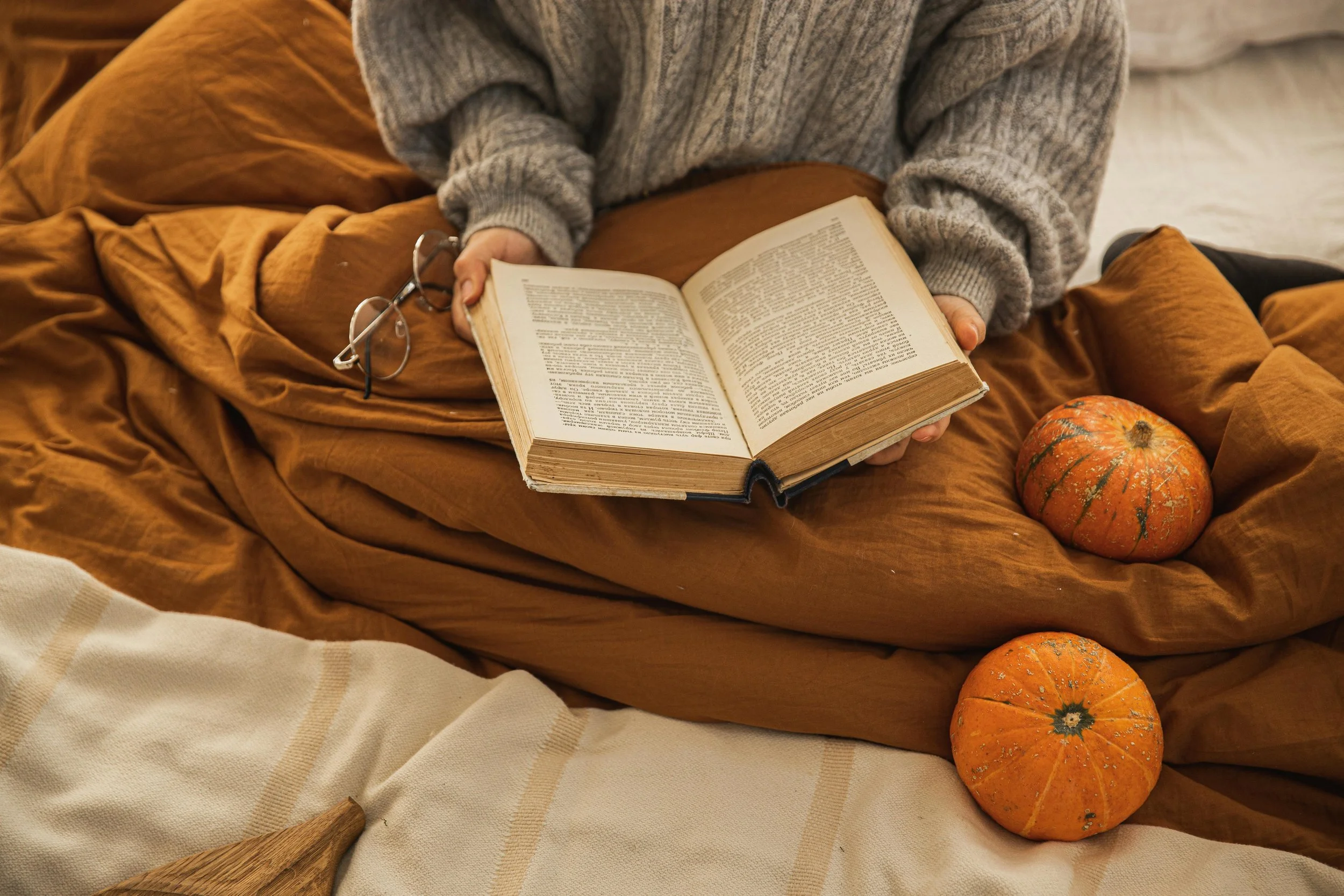 A student holds a book open on a bed