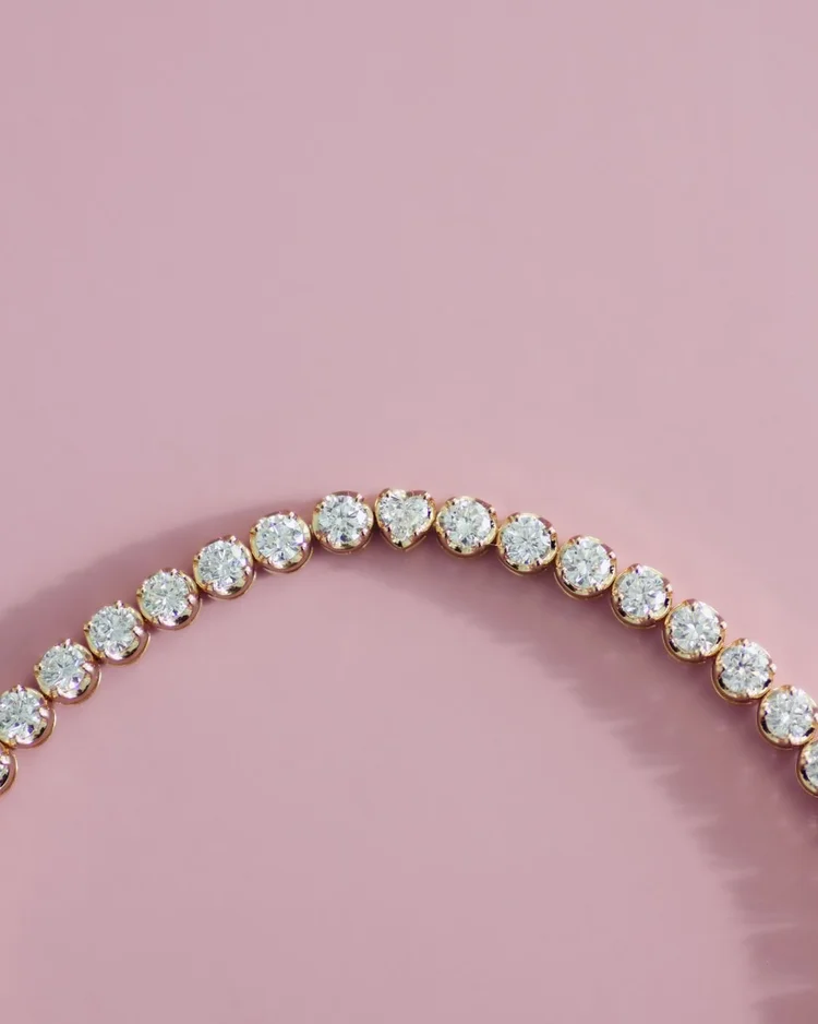 A gold tennis bracelet set with three heart-shaped diamonds