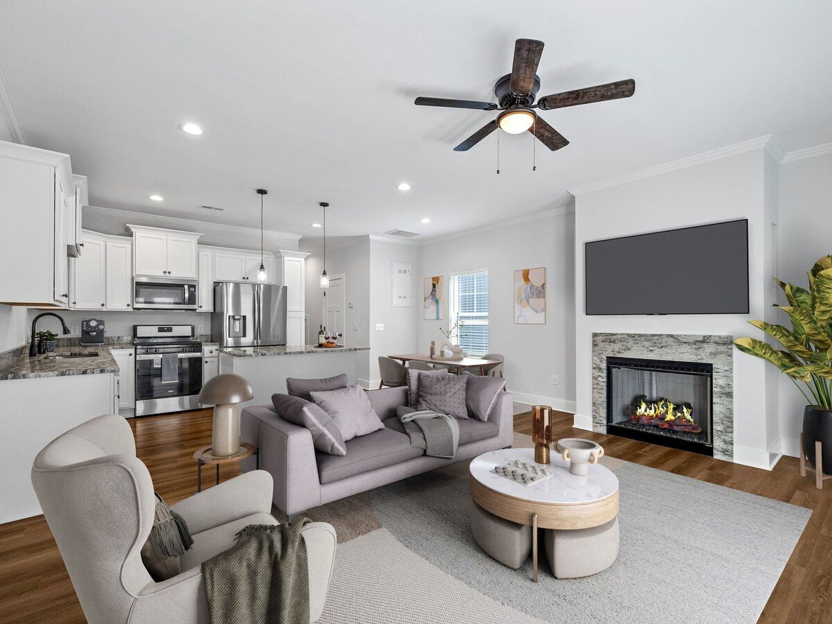 Open-concept kitchen and living area at Townes at Converse in Spartanburg, SC, featuring white cabinetry, hardwood floors and a fireplace.