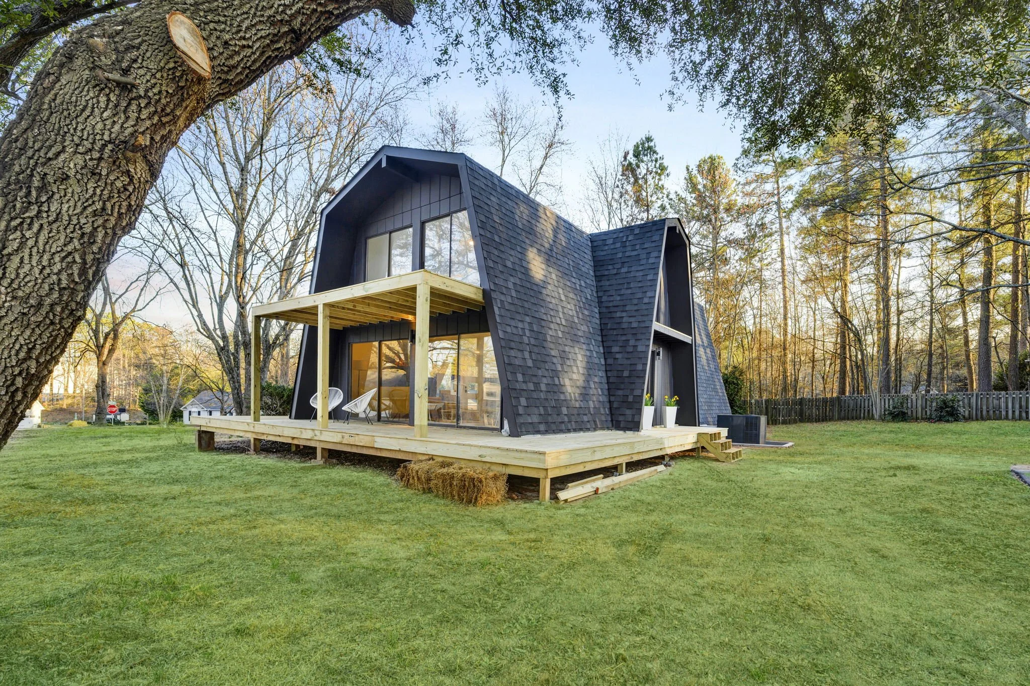 Renovated contemporary home at 112 Wayland Drive in Duncan, SC, featuring distinctive gambrel-style rooflines, dark exterior shingles, large windows, and a wraparound wooden deck.