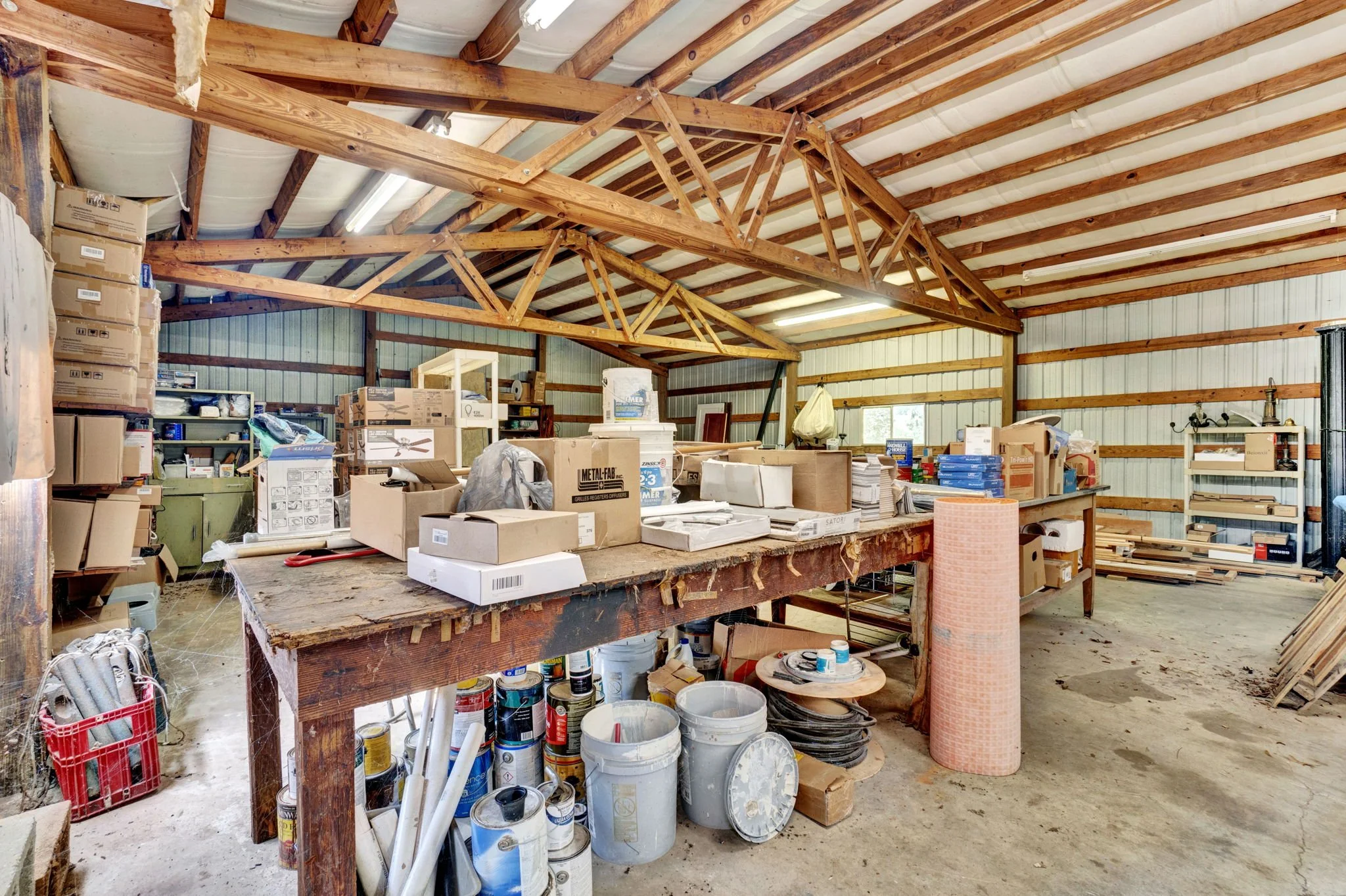 Spacious detached workshop at 1317 Hub Wilson Road in Landrum, SC, featuring exposed timber roof trusses, metal siding, workbenches, and ample storage space.