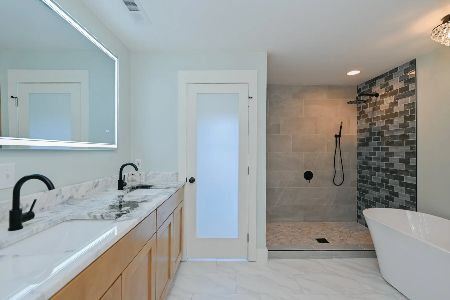 Renovated primary bathroom at 1334 Jameson Road in Easley, SC, featuring a double vanity with marble countertops, natural wood cabinetry, black fixtures, a walk-in tiled shower, and a freestanding bathtub.