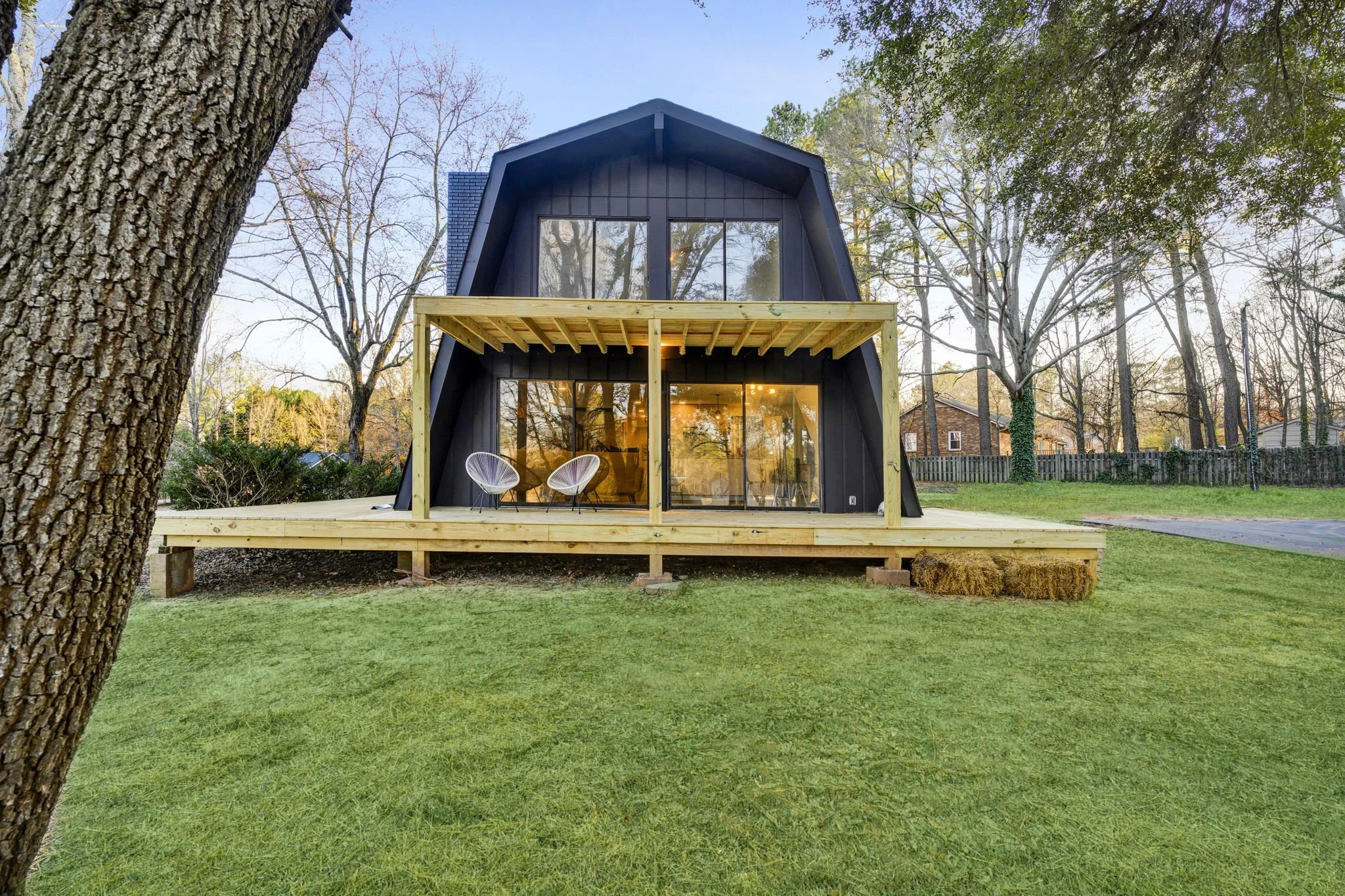Renovated contemporary home at 112 Wayland Drive in Duncan, SC, featuring dark exterior siding, large windows, and a two-story wooden deck overlooking the lawn.