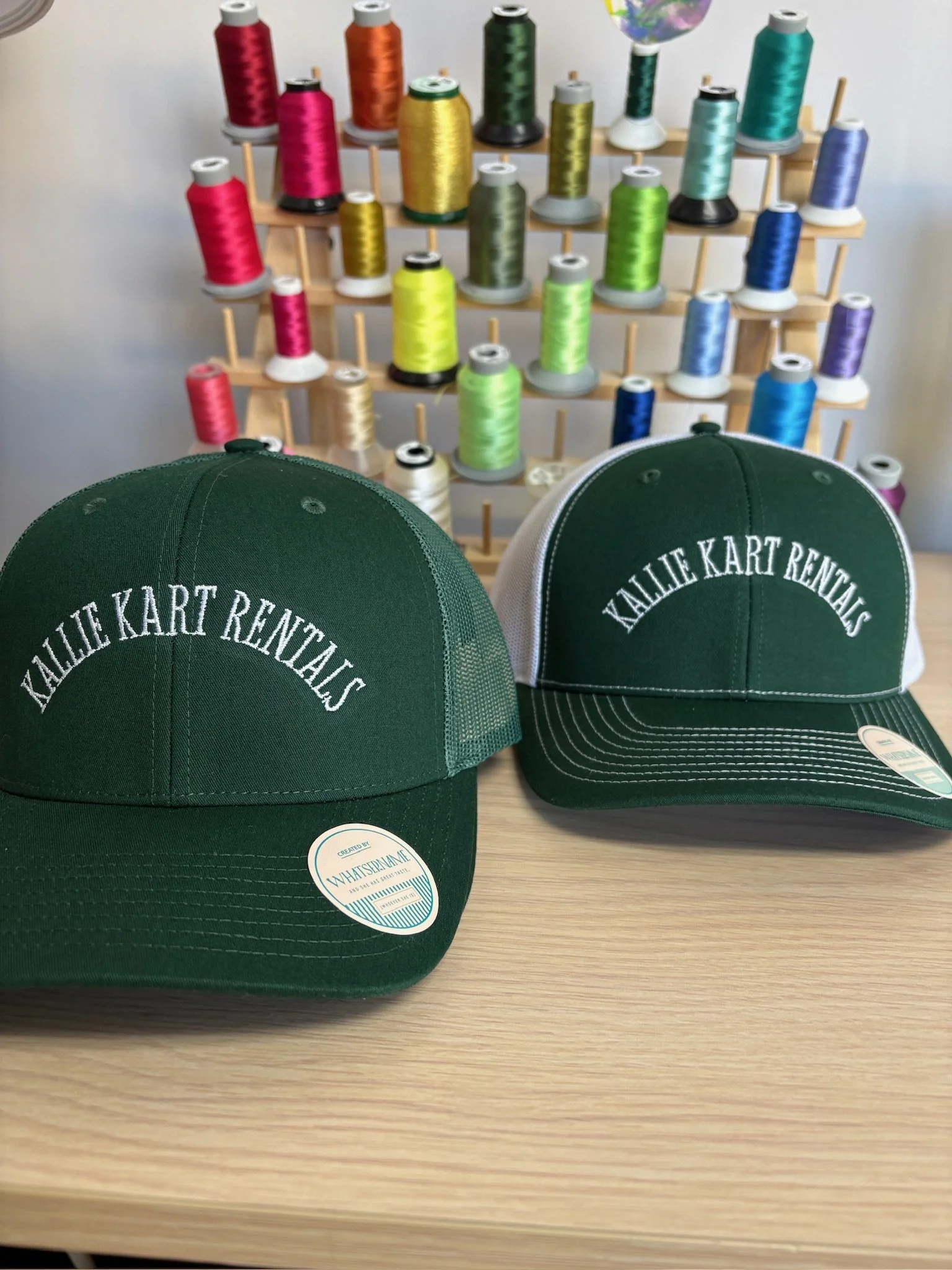 Two custom embroidered green and white caps with local small business branding.