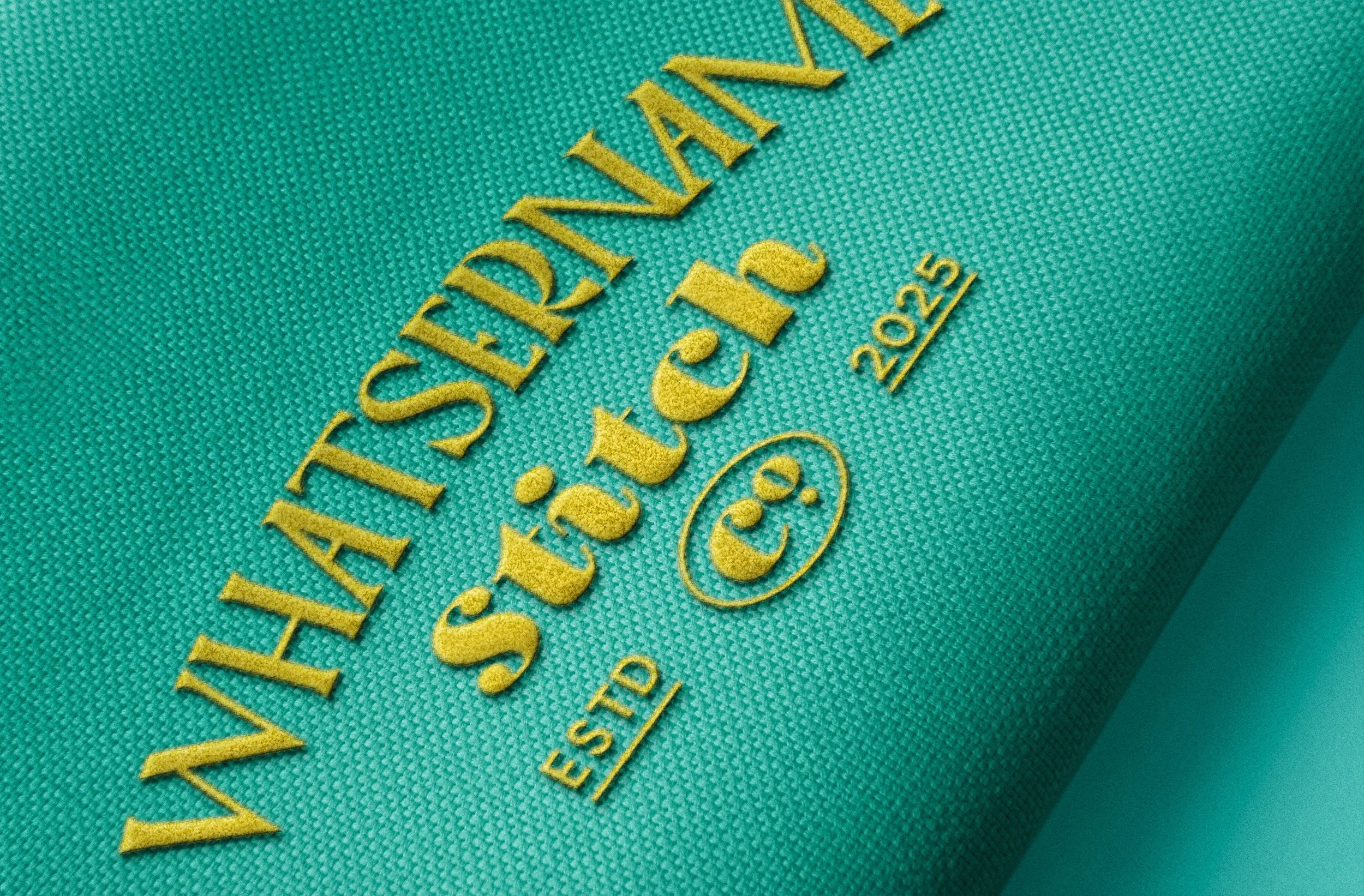 Close-up of a teal fabric with puff embroidered text that reads "Whatsername Stitch Co".