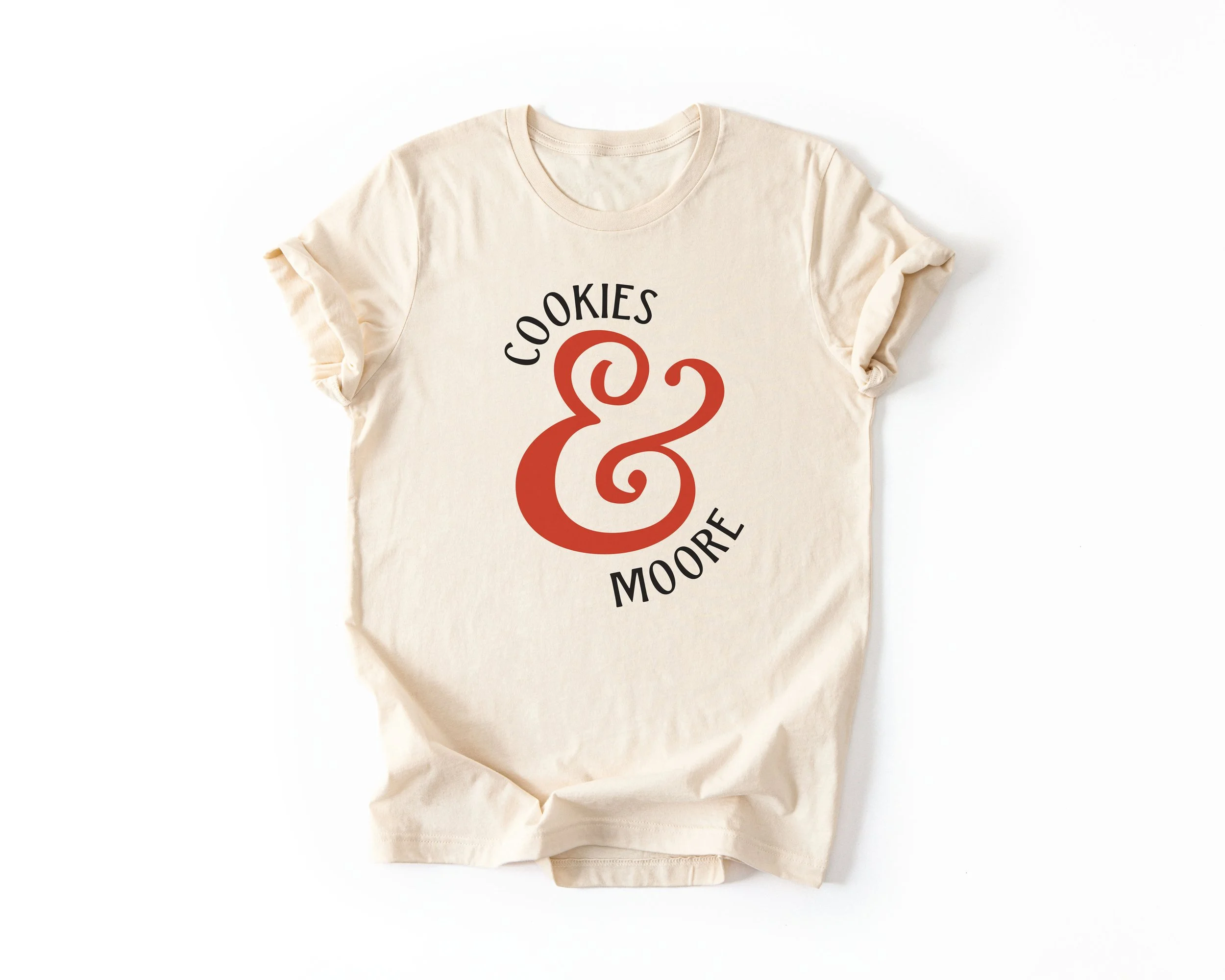 Cream-colored T-shirt with branding of local small business "Cookies & Moore" and a large decorative ampersand in the center.