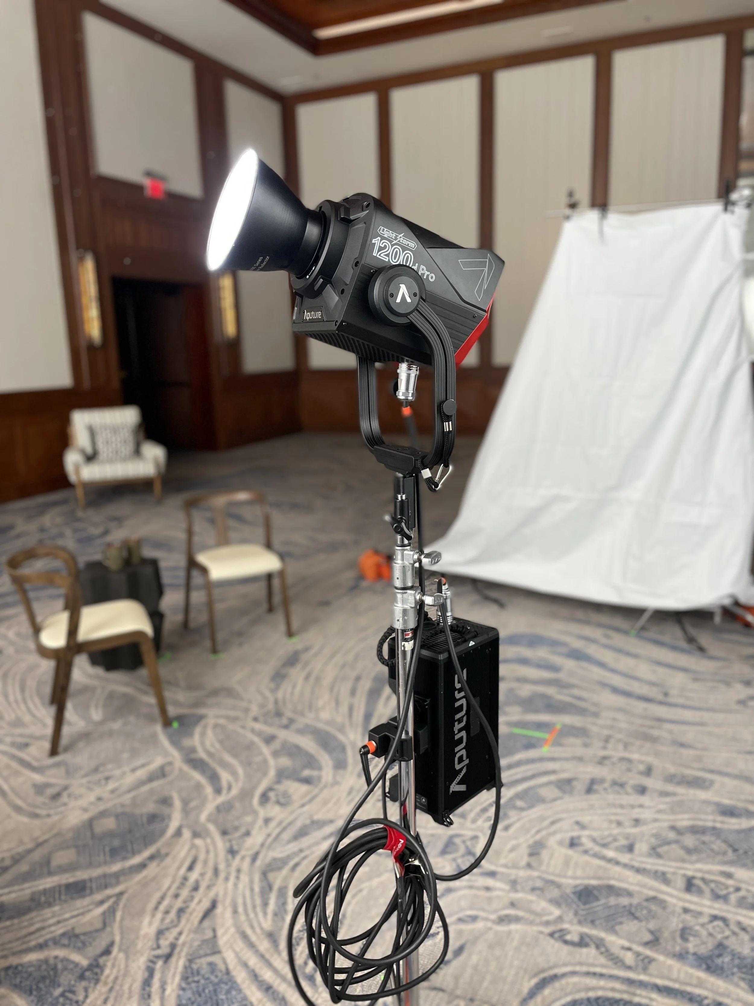 Professional lighting equipment setup in a conference room with chairs and a backdrop.