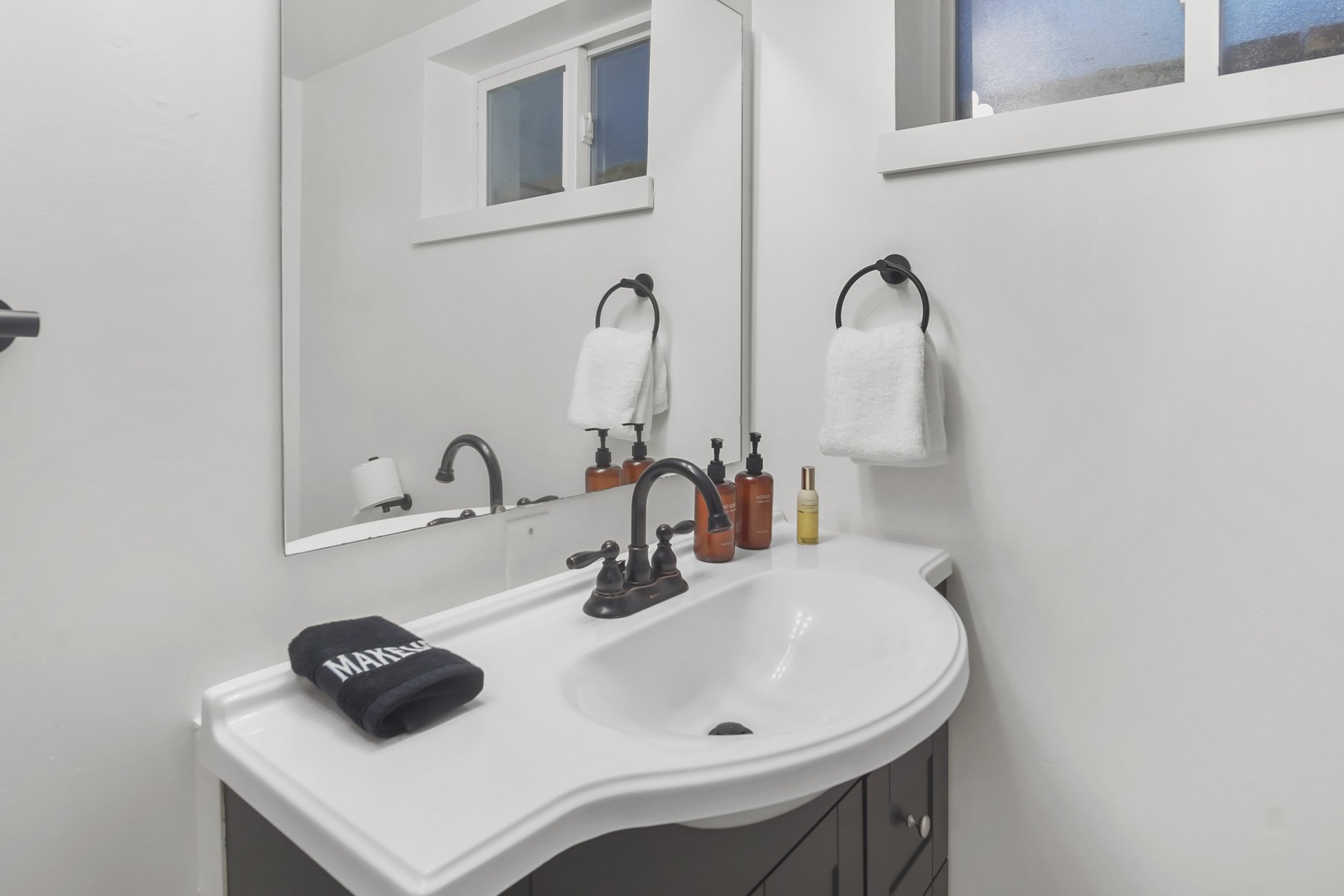 A close up of the counter top with soap, lotion, room freshener and towels