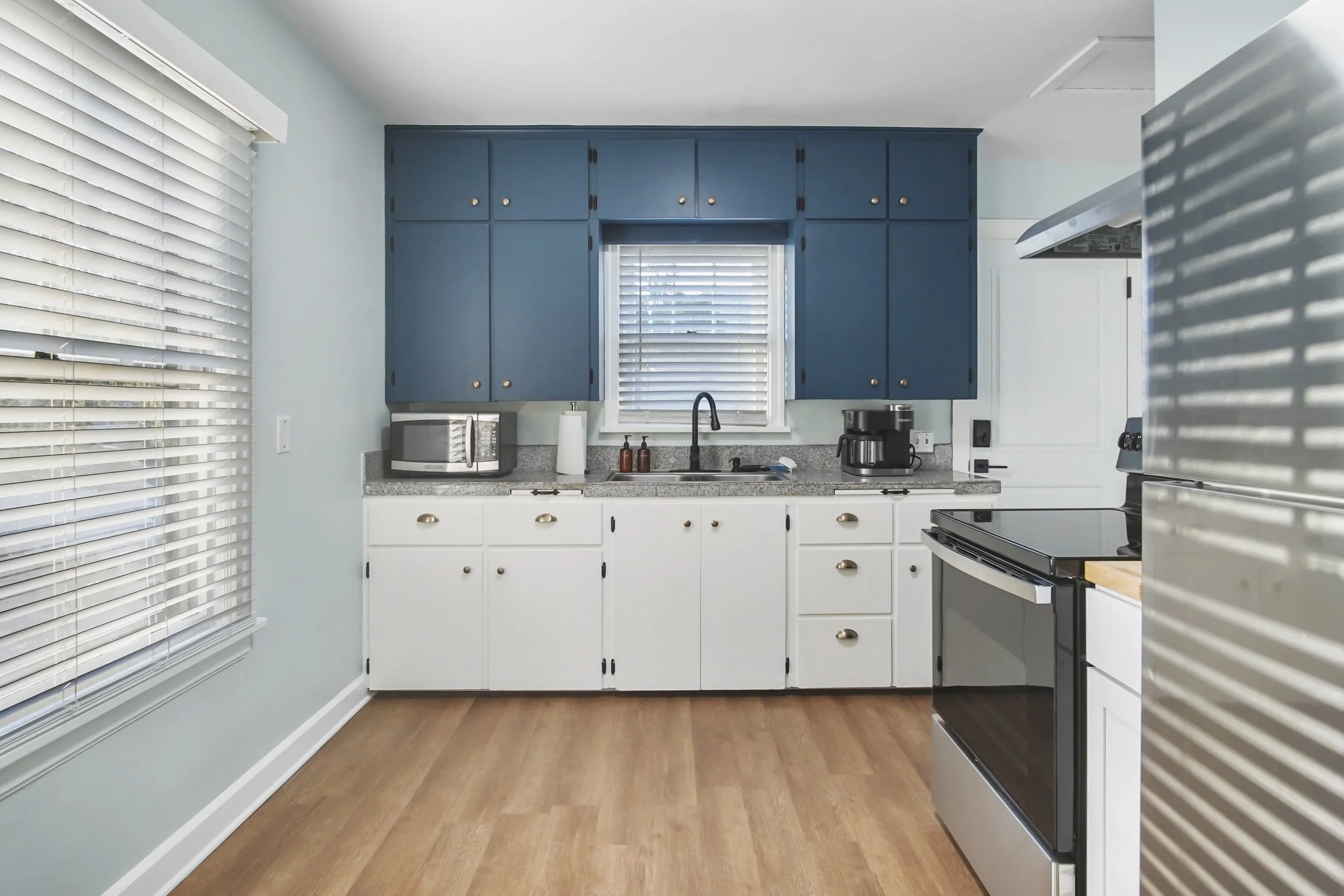 A blue and white kitchen with gold and black accents. Fully equipped with all needed appliance and necessities