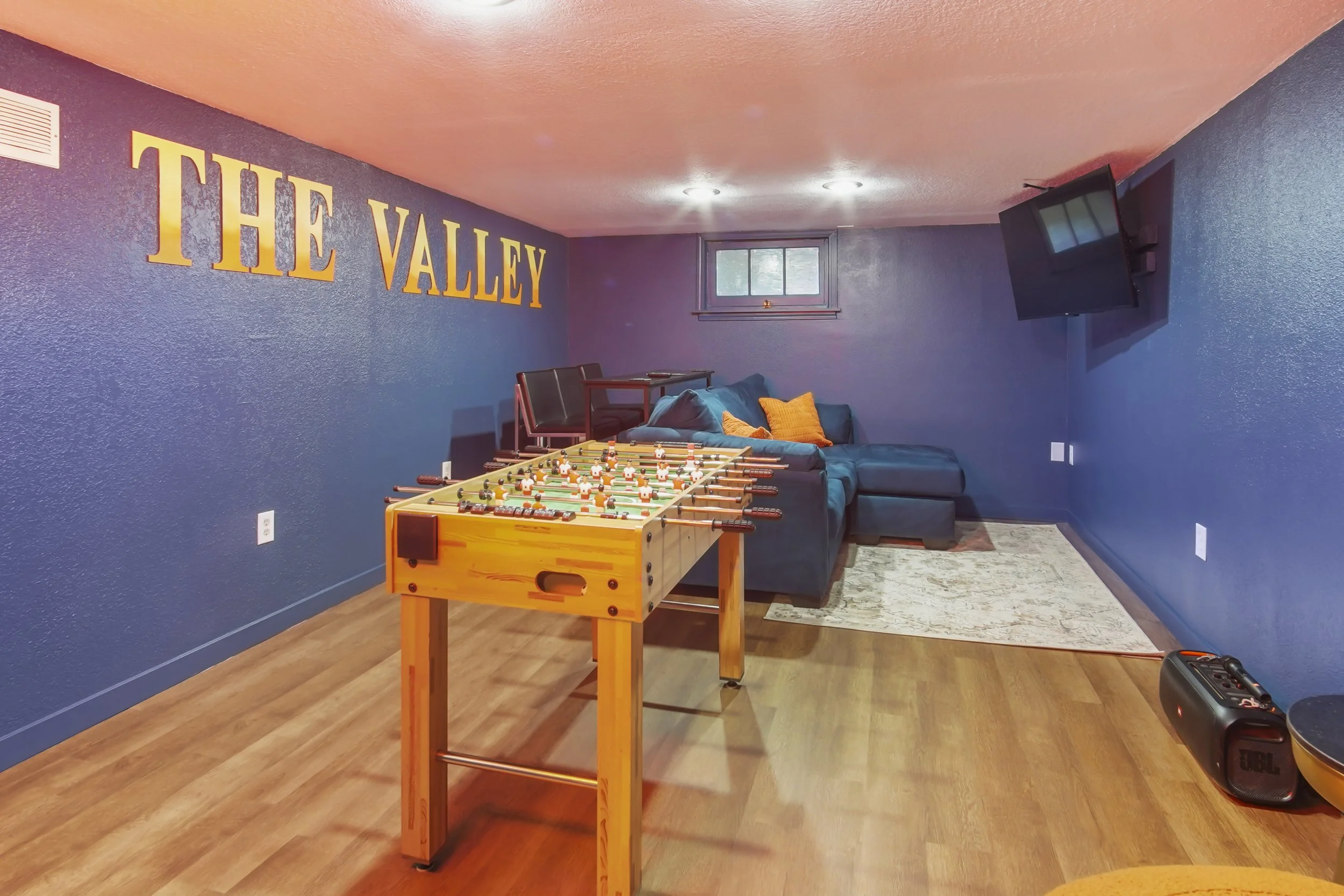The Valley Home in bright orange and moody blues. A foosball table, JBL speaker, and Roku Tv
