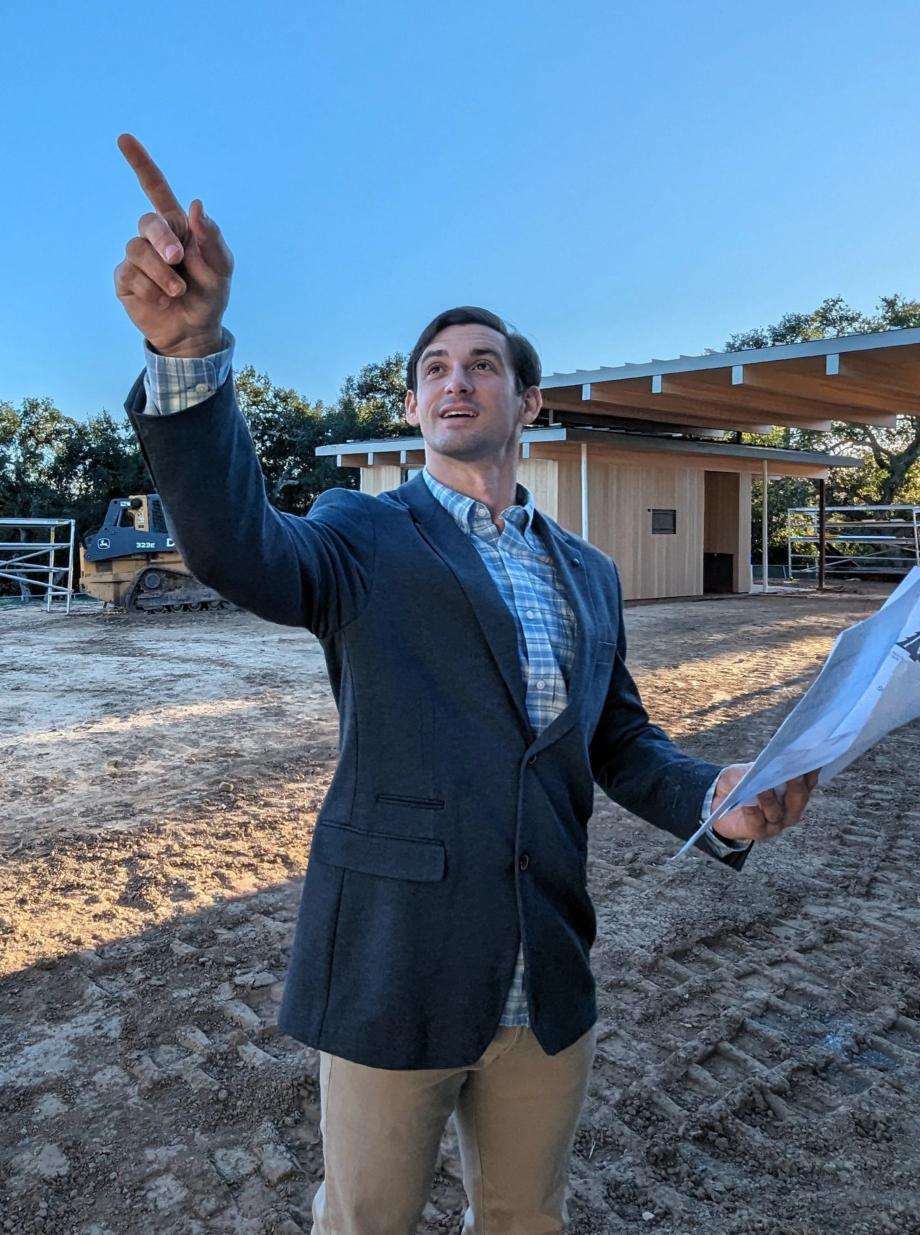 Security project manager on-site at a premium residential construction build holding blueprints and pointing out physical camera placement locations.