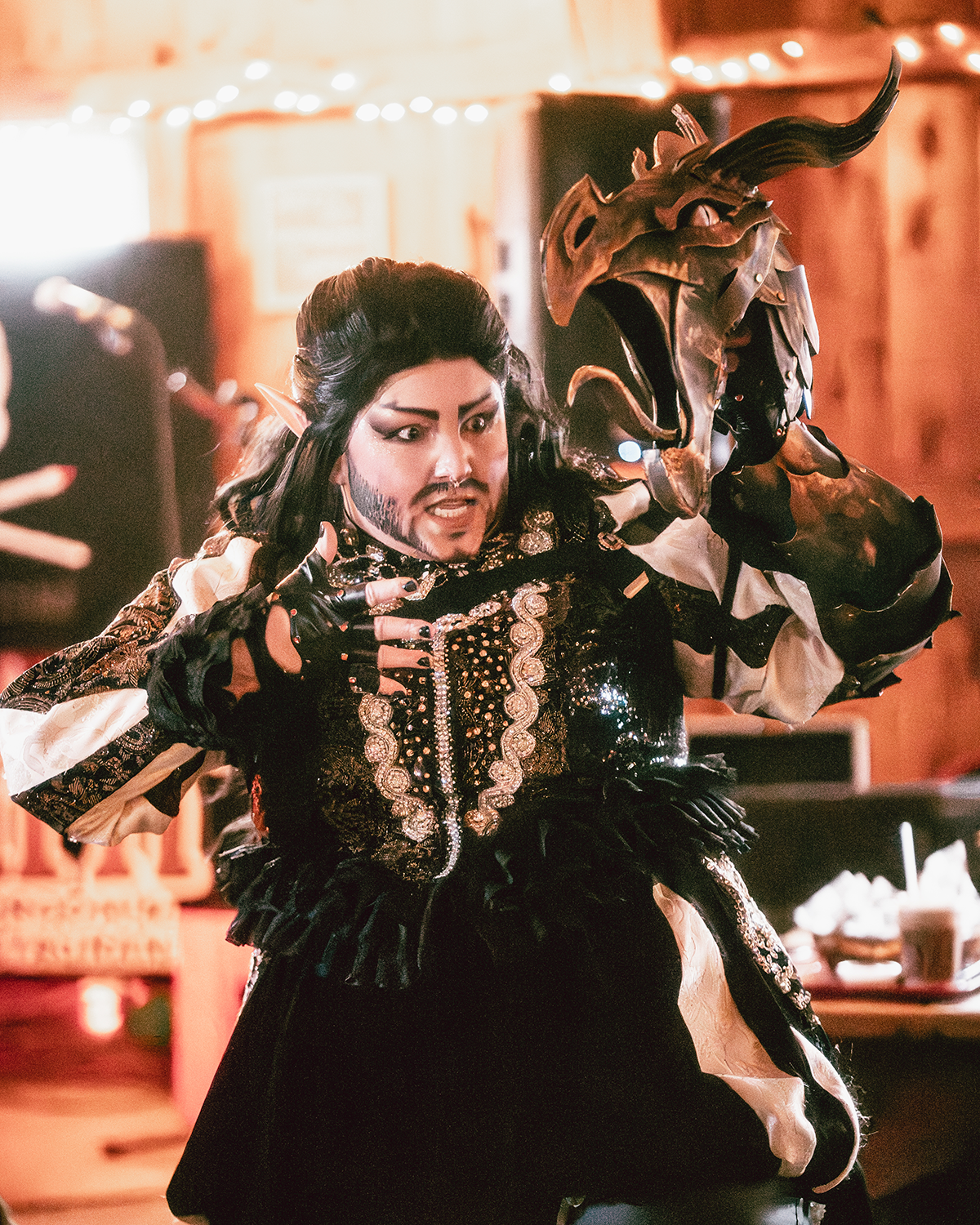 Person dressed in elaborate costume with a dragon head mask, pointing with fingers