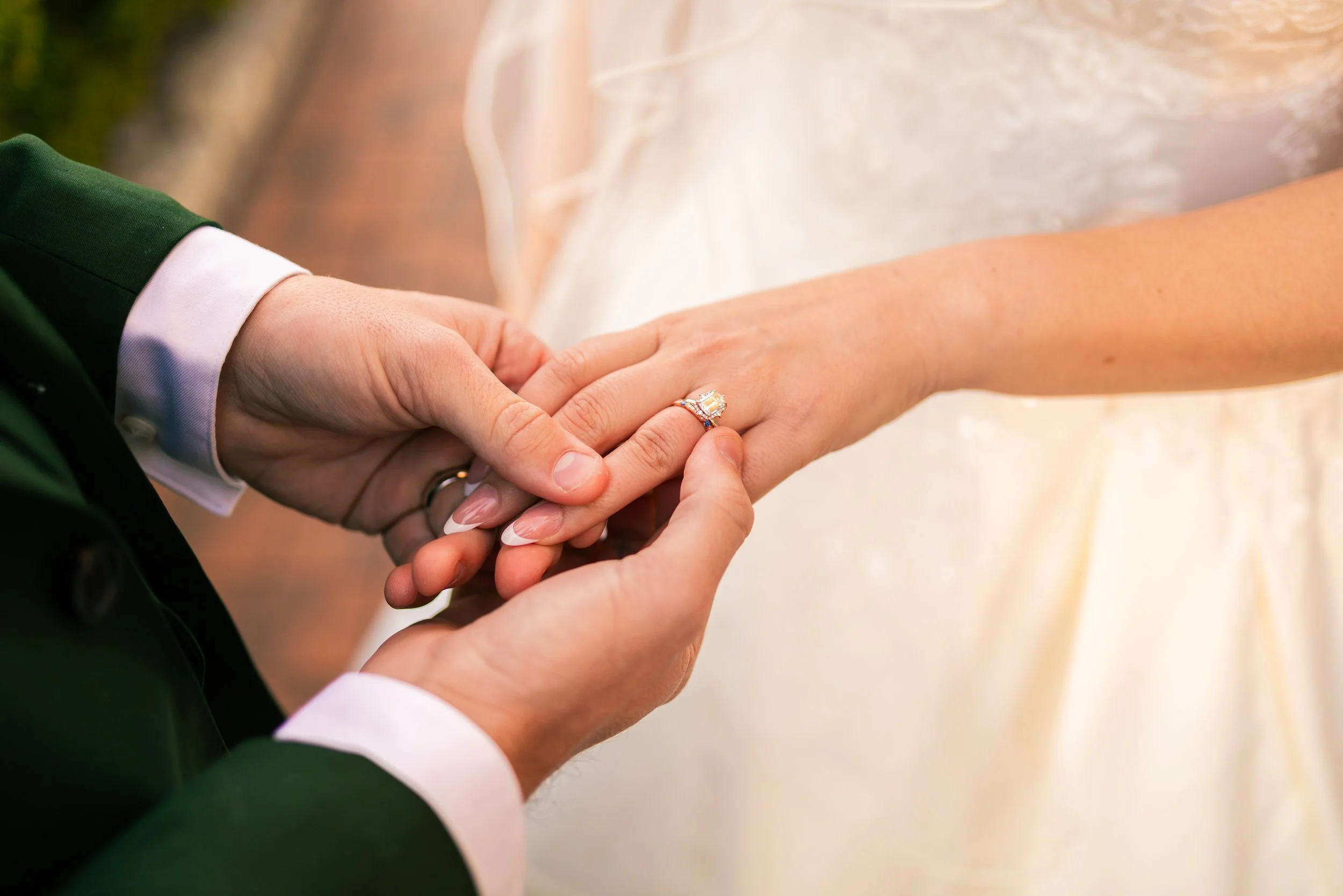 Close-up of a groom placing a wedding ring on a bride's finger during a wedding ceremony.