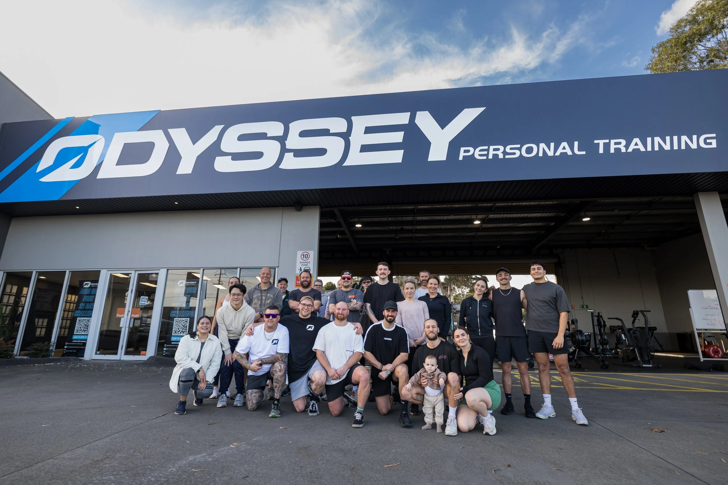 Group of people standing and kneeling in front of Odyssey Personal Training center
