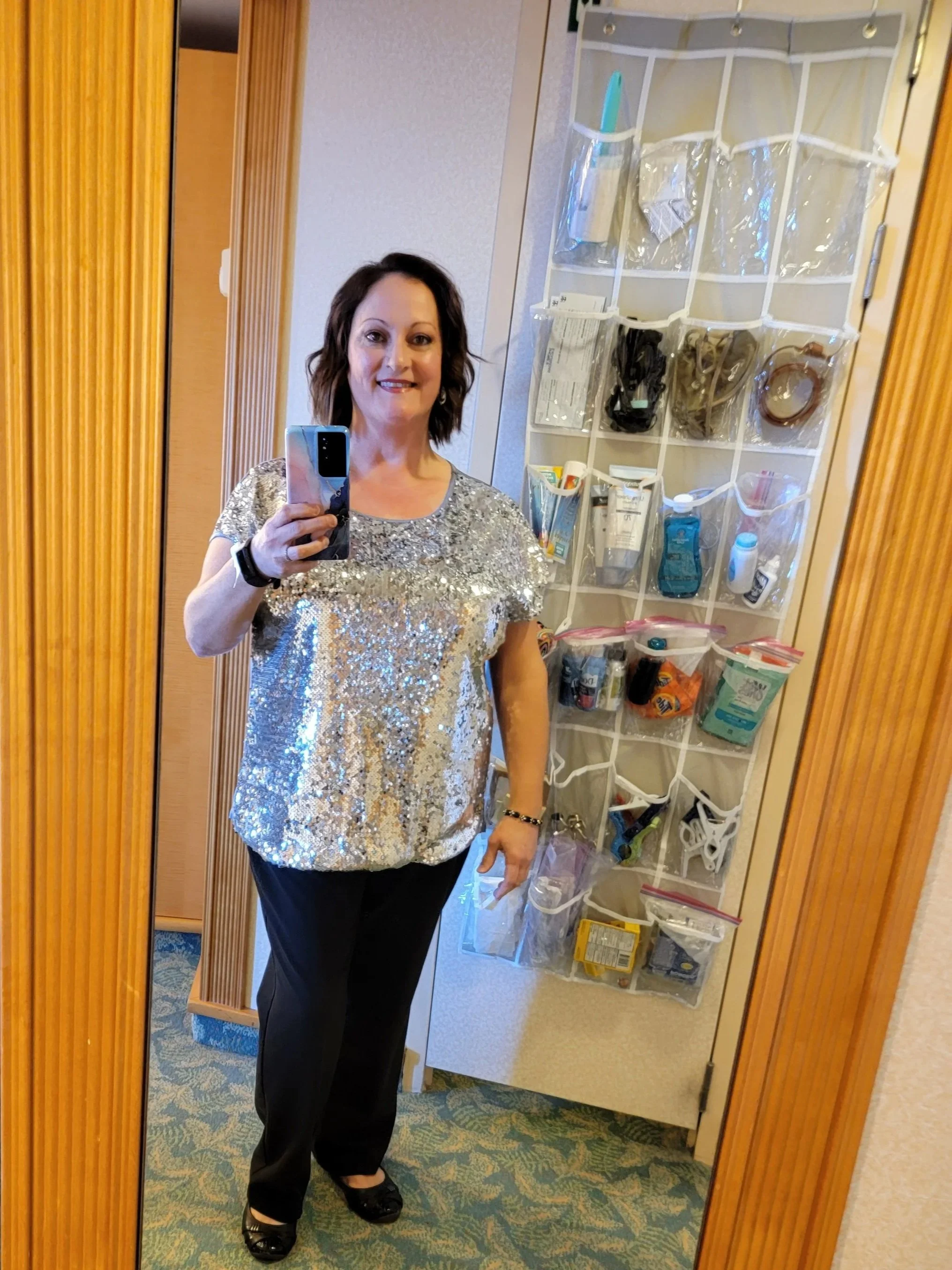 Woman taking selfie in front of mirror with hanging shoe organizer behind her