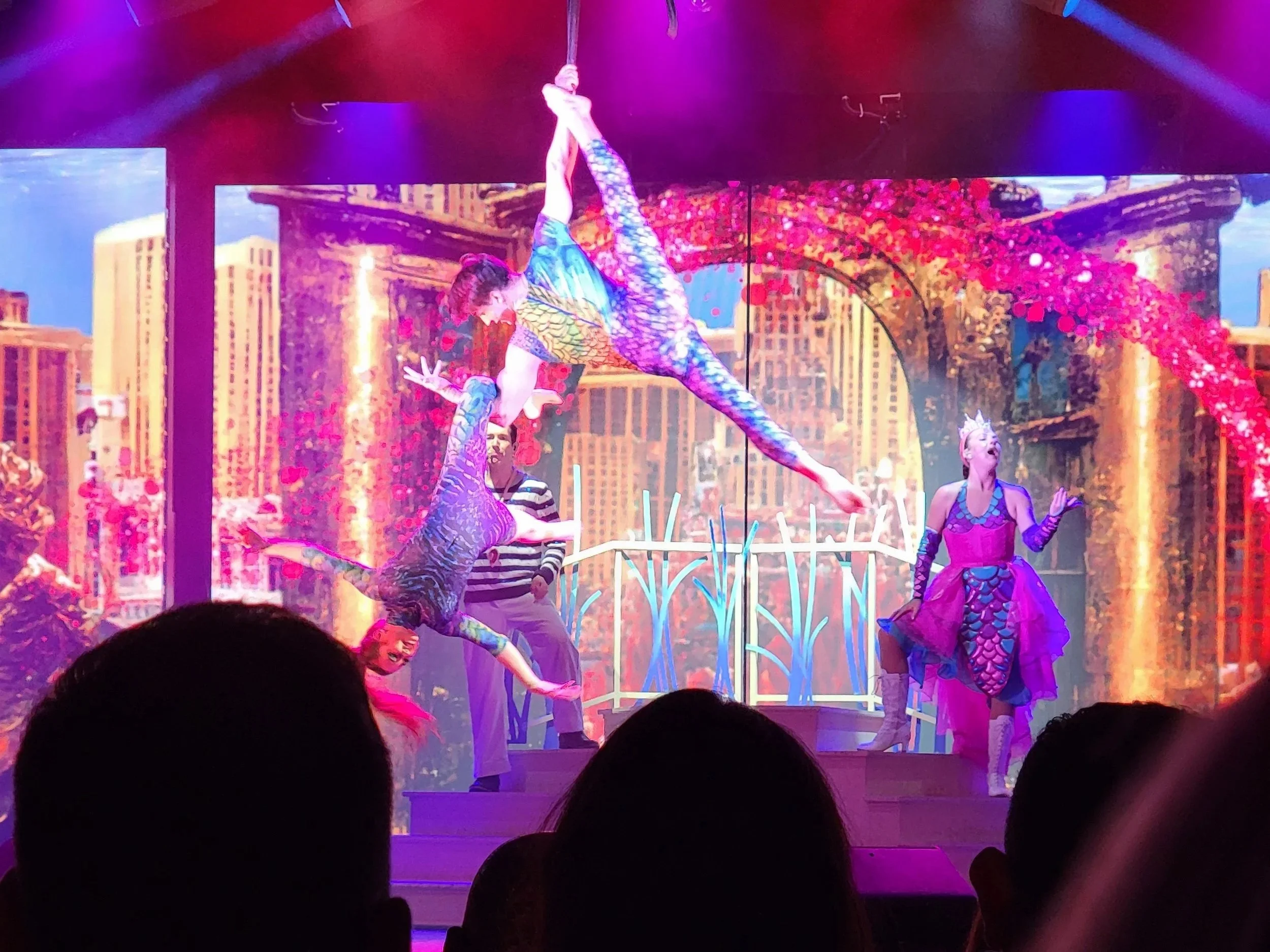 Two arial artists performing in front of singers