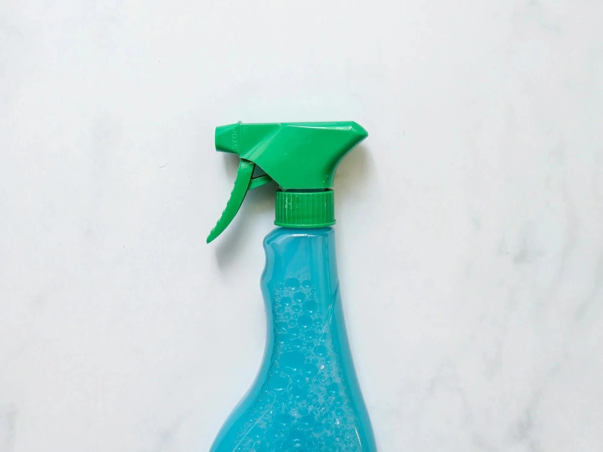 blue spray bottle with green lid on marble