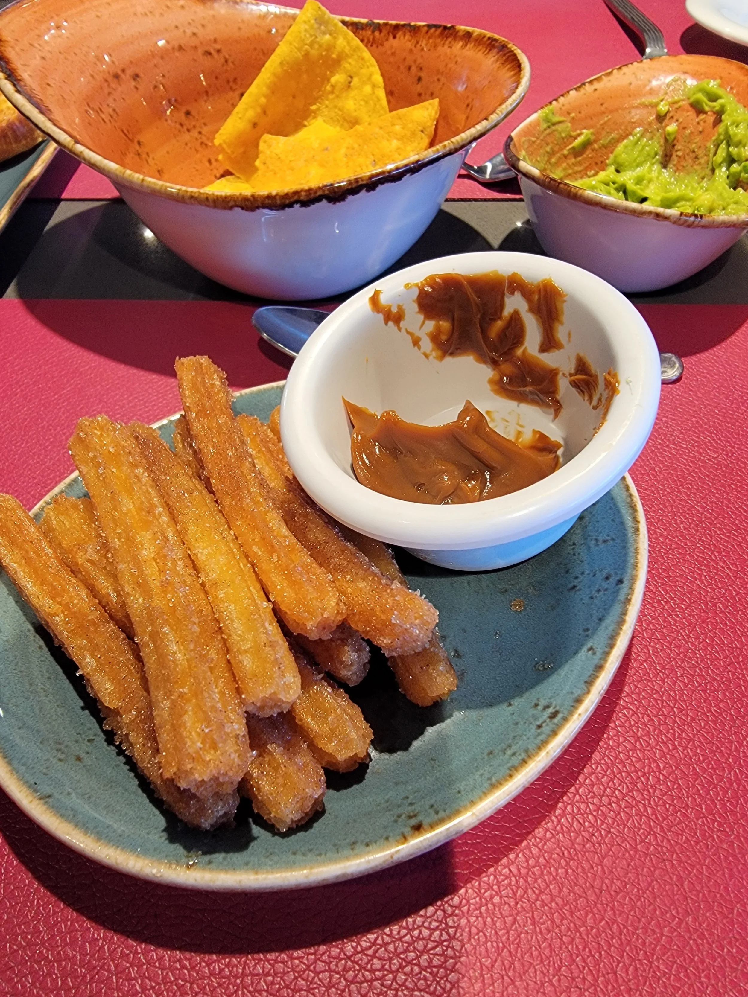 Churros with caramel on a blue plate and red table