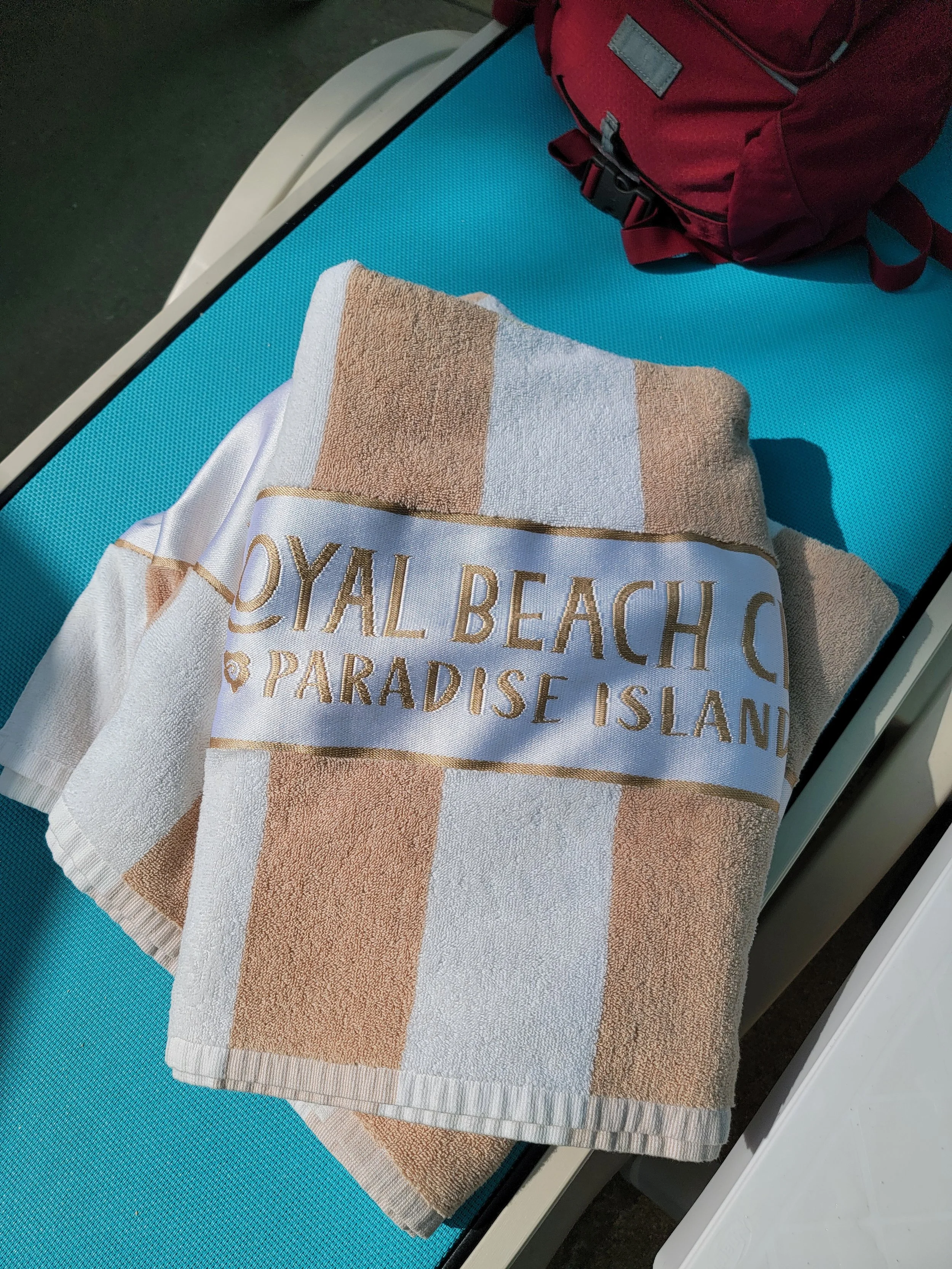 Tan and white beach towel on blue lounger