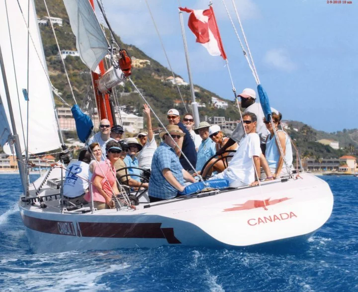 Monohull 12 metre yacht sailing in harbor with people on it