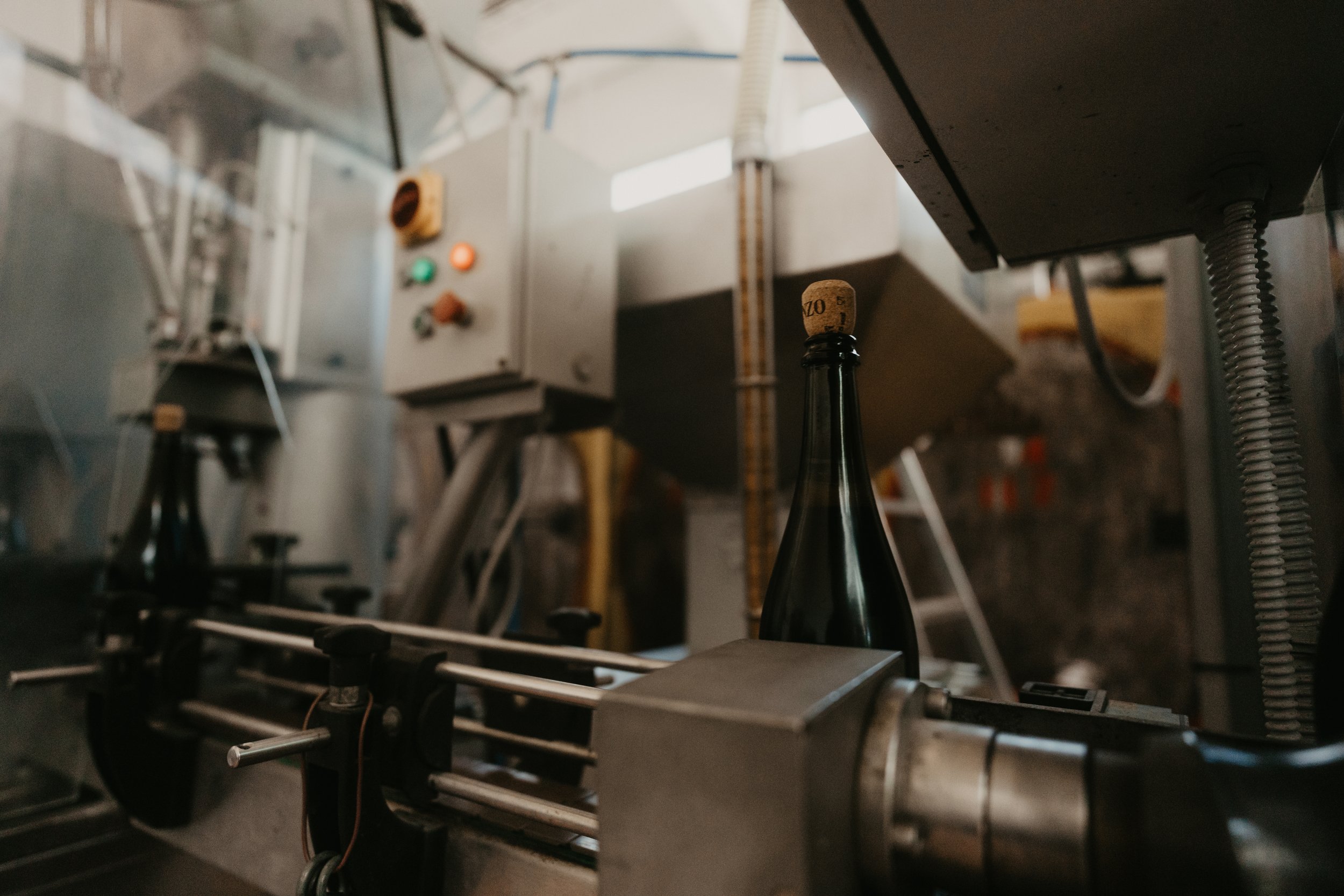 A brewery bottling line with a dark glass bottle and cork, part of machinery in a brewery or bottling facility.