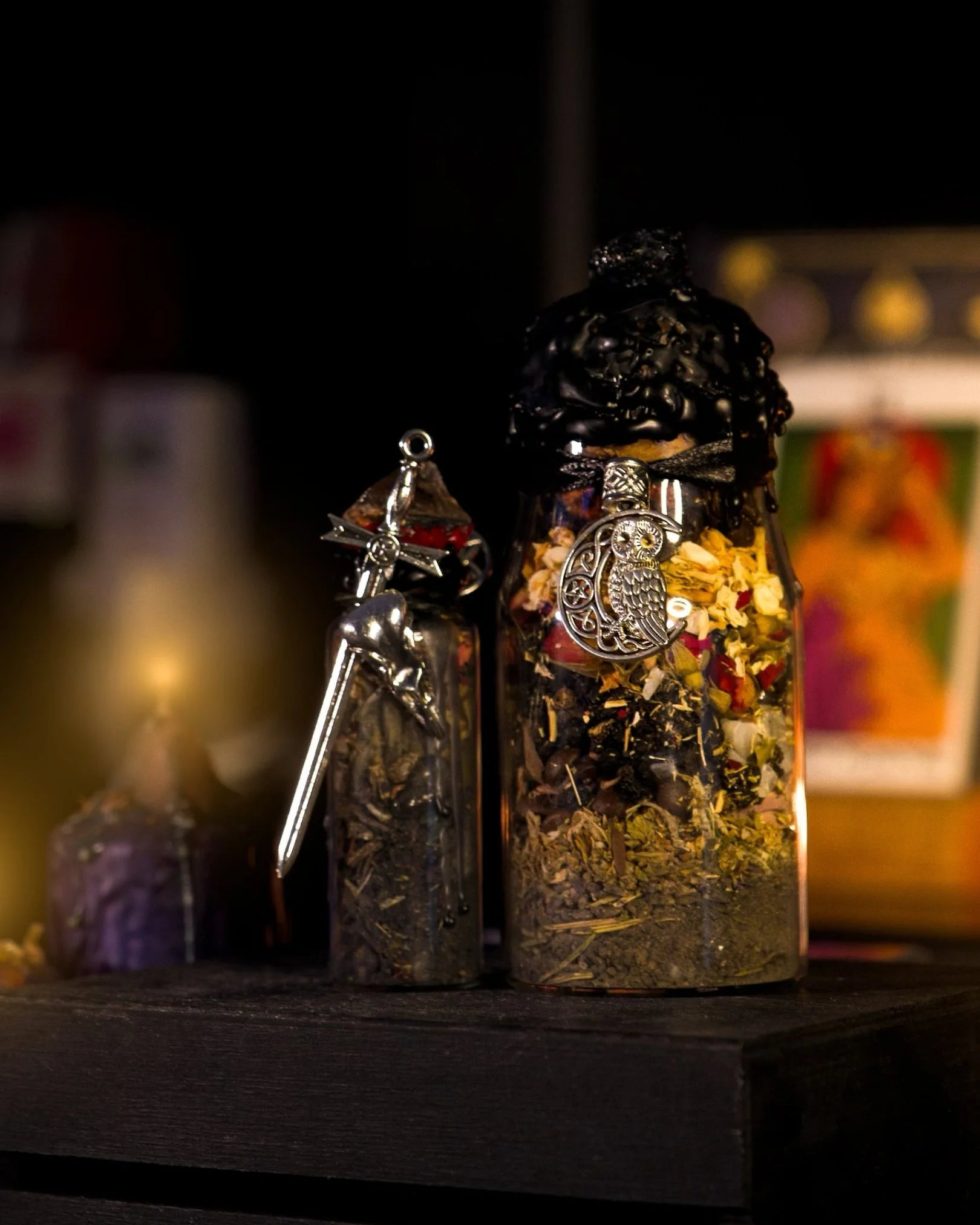 Glass jars filled with dried herbs and flowers, decorated with jewelry charms, on a dark wooden surface.