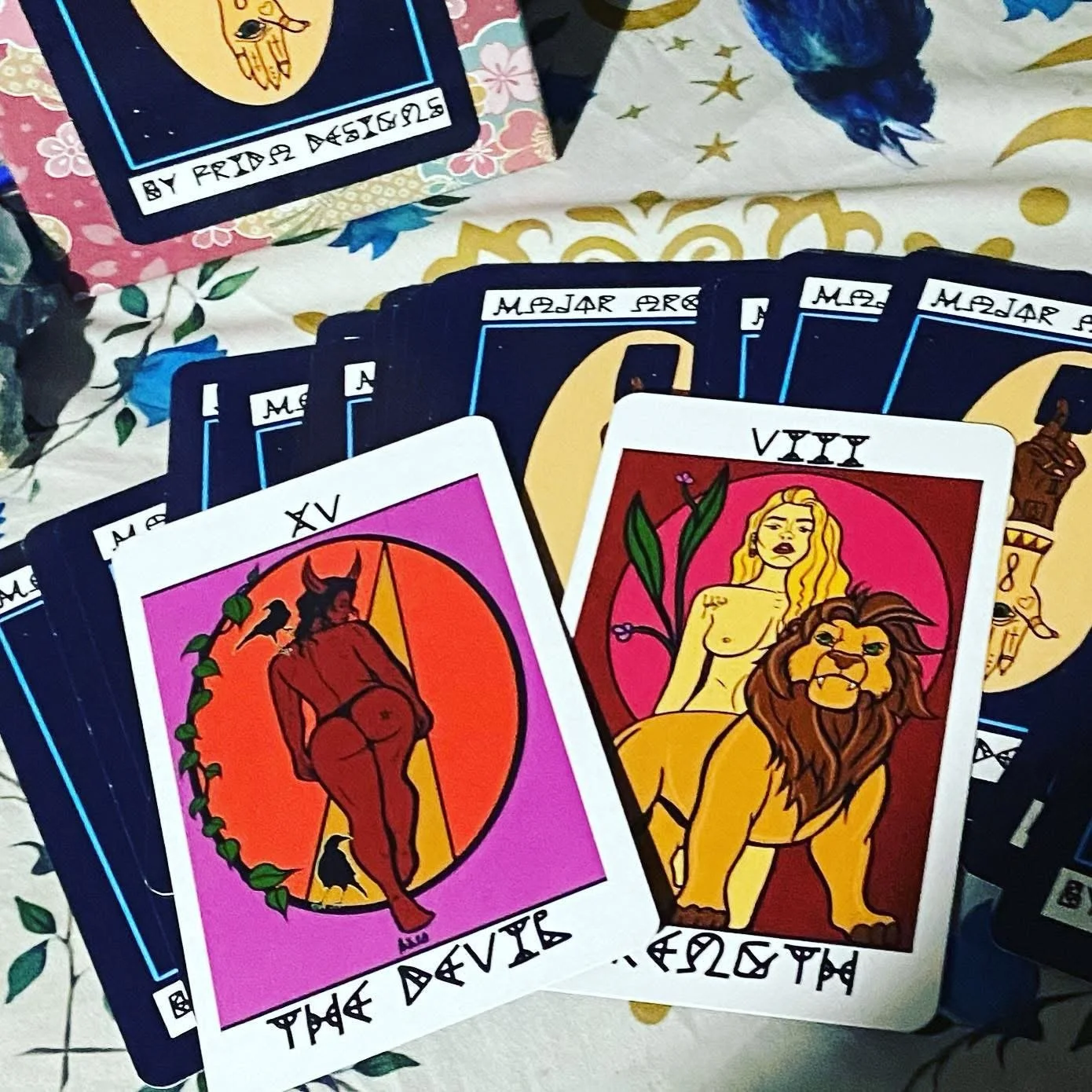 Two illustrated tarot cards, one depicting a devil and the other a lion with a woman, placed on a deck with additional tarot cards fanned out behind them.