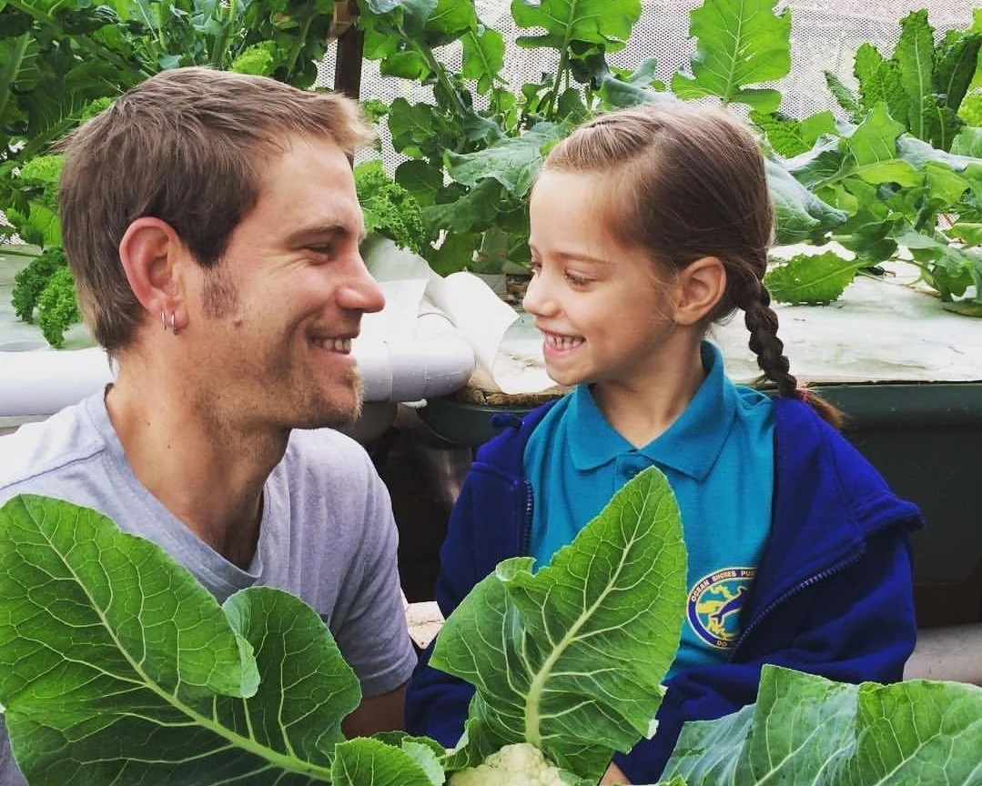 Man with a young girls smiling inside of a grenhouse
