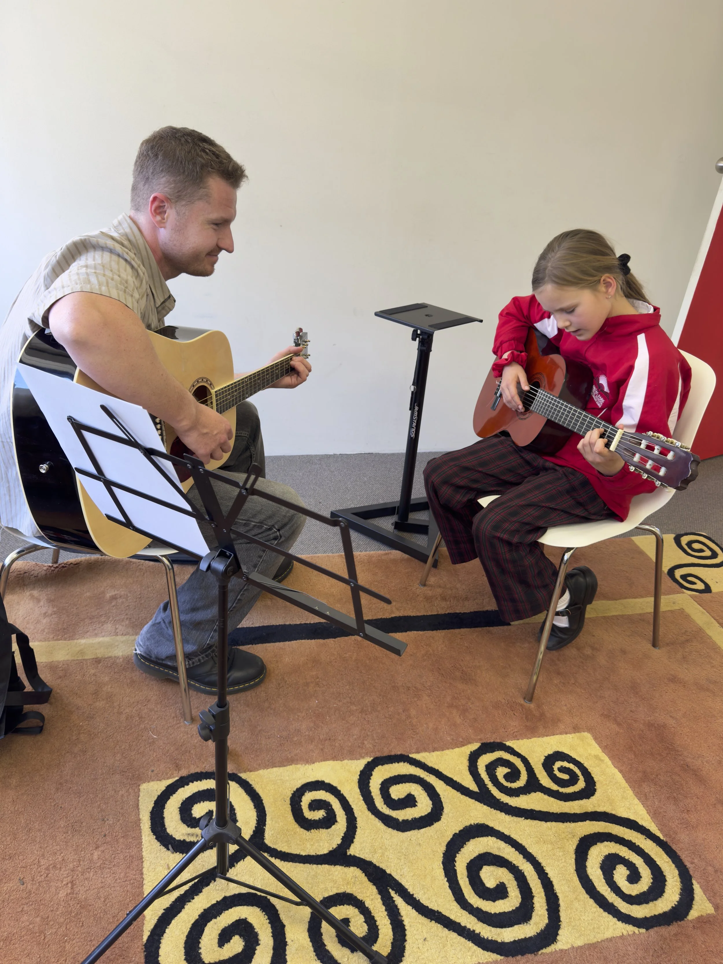 Tutor Ollie teaching guitar to a student