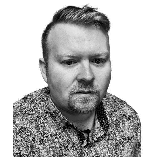 Black and white portrait of a man with short, styled hair and a goatee, wearing a patterned shirt.