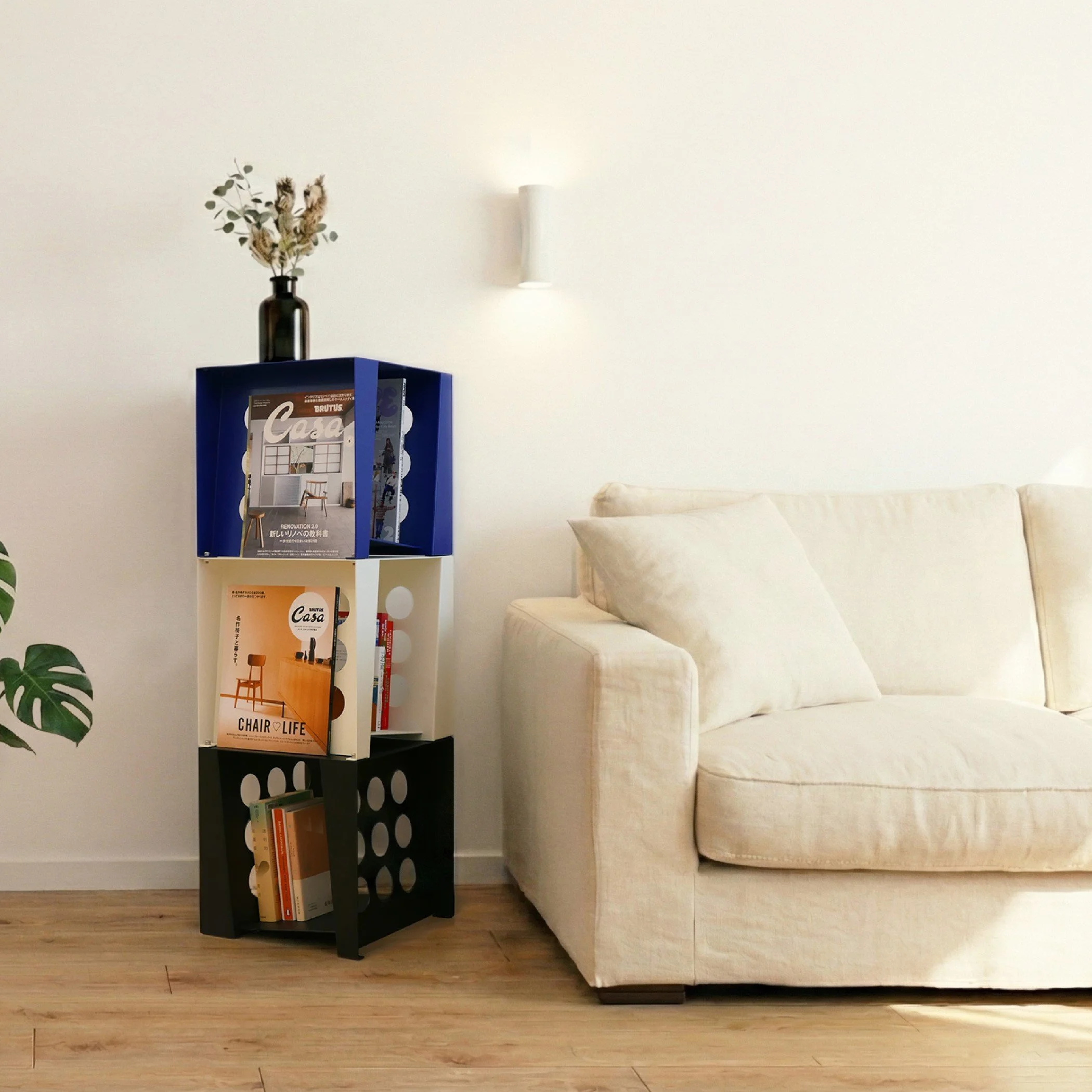 Living room corner with white sofa and a colorful bookshelf, including books and a plant.