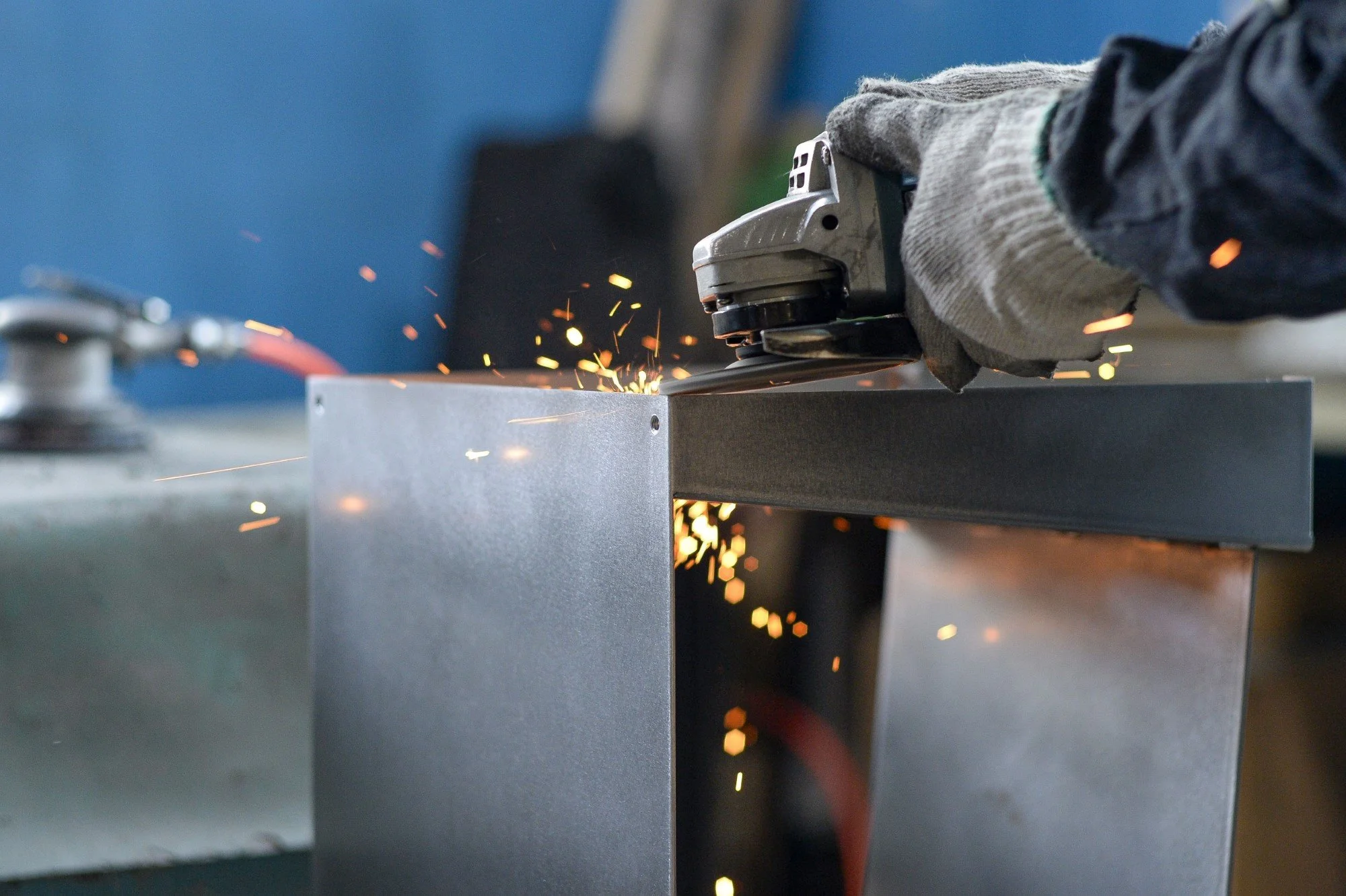 Close-up of a craftsman's hands polishing the steel surface of the Tilted Book Seat.