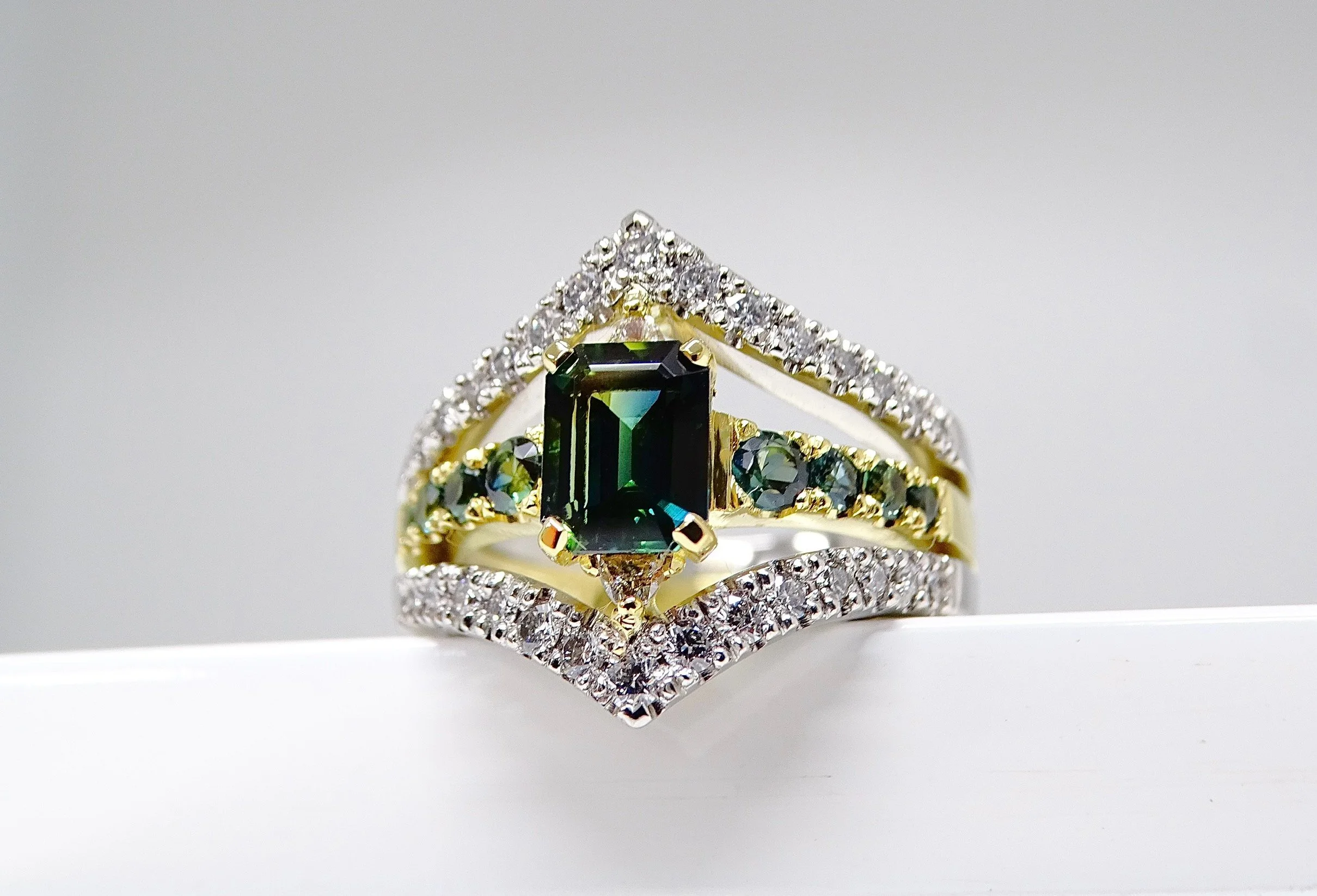 18ct yellow gold and platinum emerald cut parti sapphire ring with diamond set rails. 