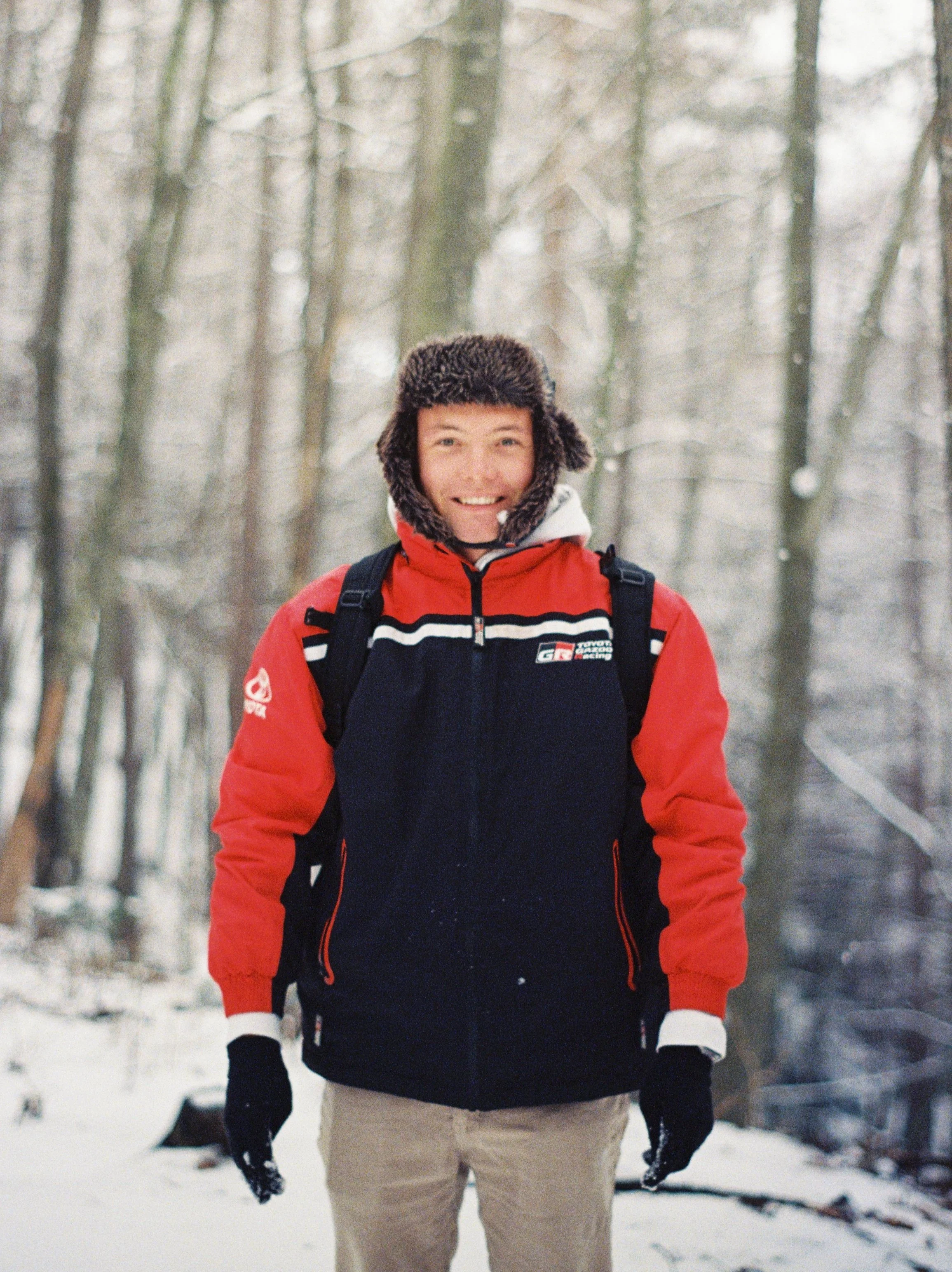 Person wearing a winter jacket and fur hat in a snowy forest