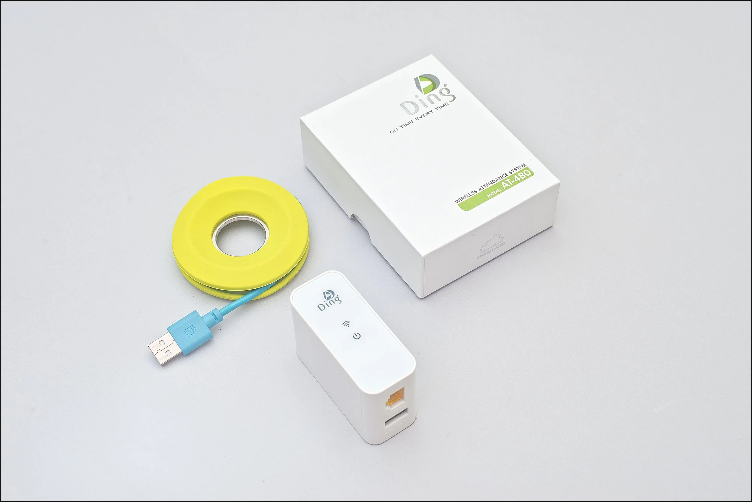 Wireless attendance system components including a yellow tracking device with blue USB connector, a white receiver with indicator lights, and a white box with branding labeled "Ding" and model number AT-480 on a light gray background.