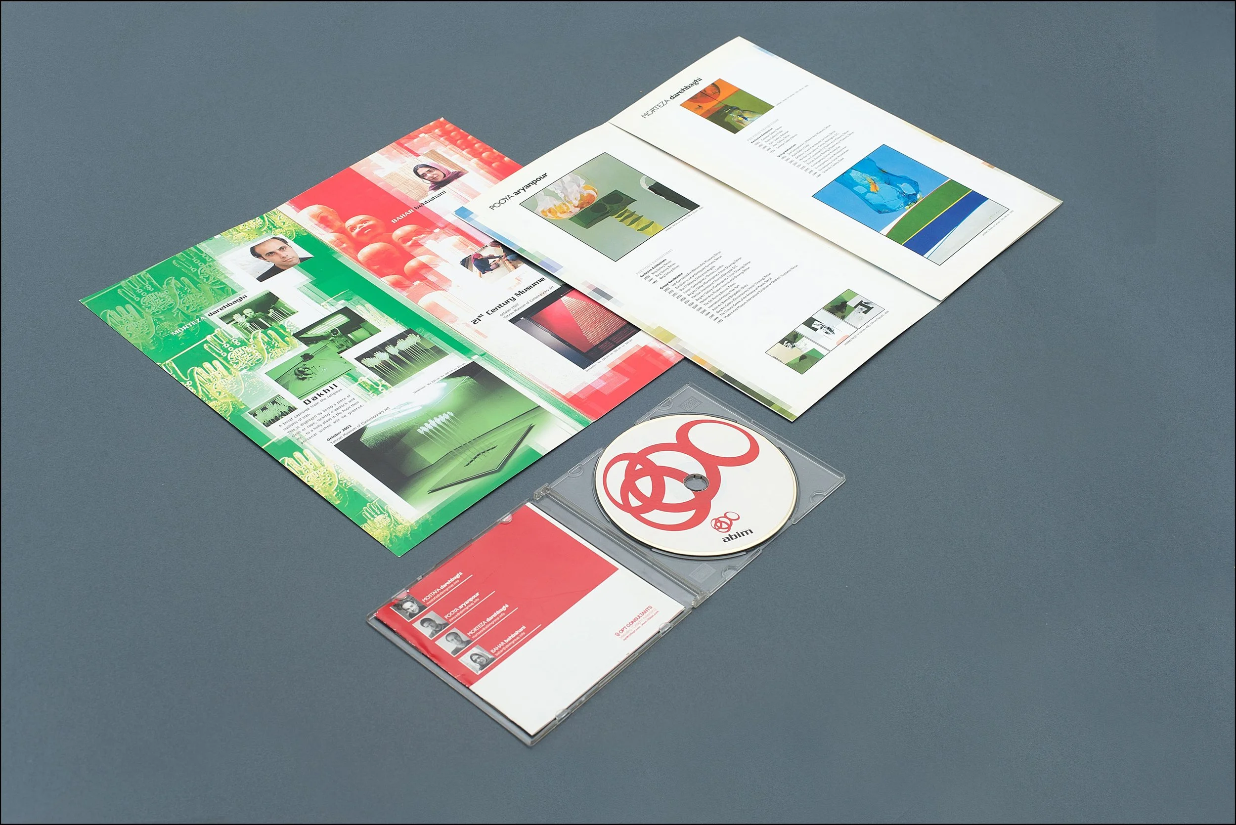 Open CD case with disc and colorful booklet pages on a gray surface.