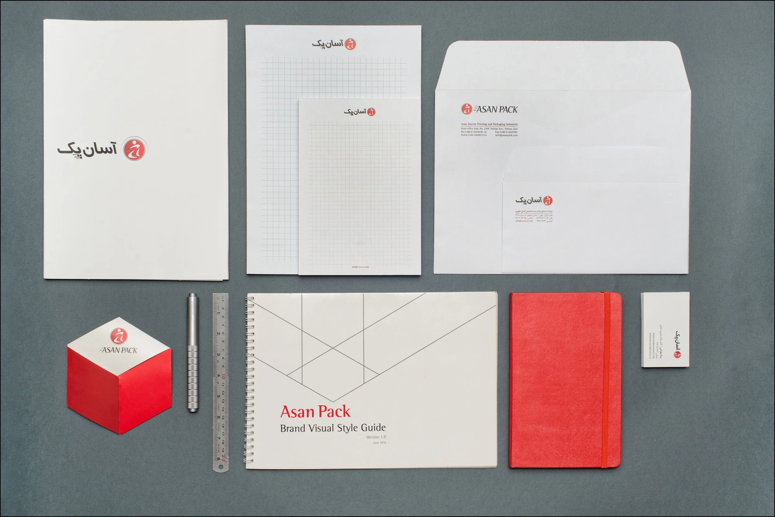A collection of stationery items including notebooks, folders, business cards, a ruler, a pen, and a small cube, all branded with the Asan Pack logo and design on a gray background.