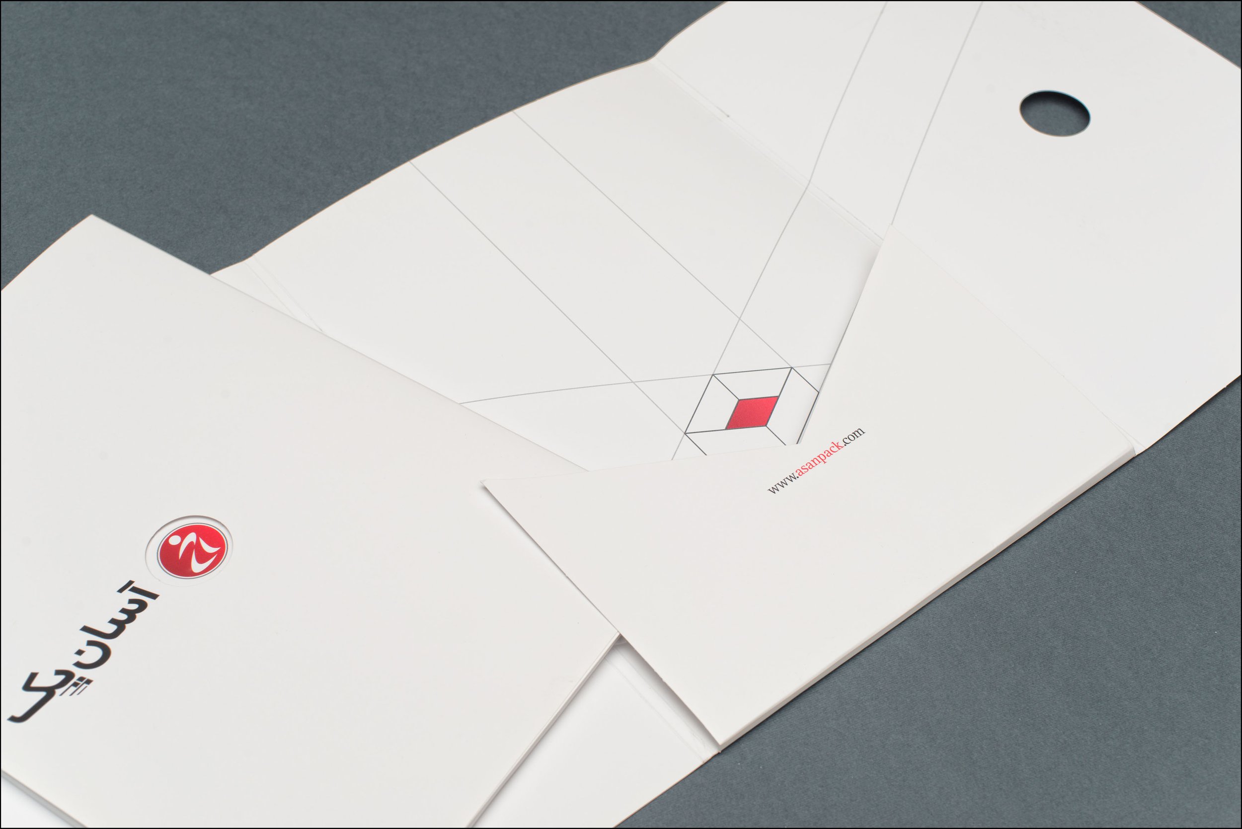 Blank white folder with Arabic logo and website URL on gray surface.