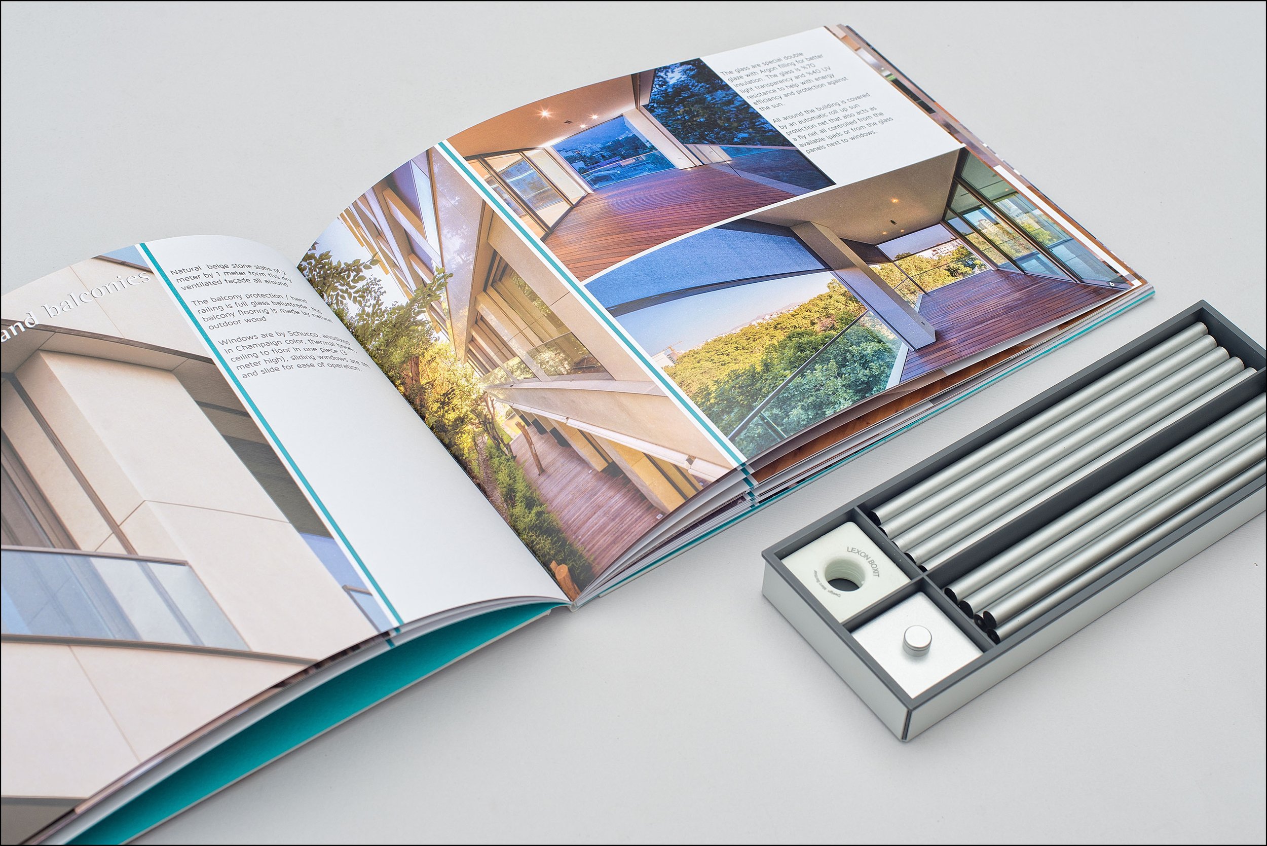 Open brochure showing images of modern balconies and glass windows, with a small organized box of different colored rods and a measuring device nearby.