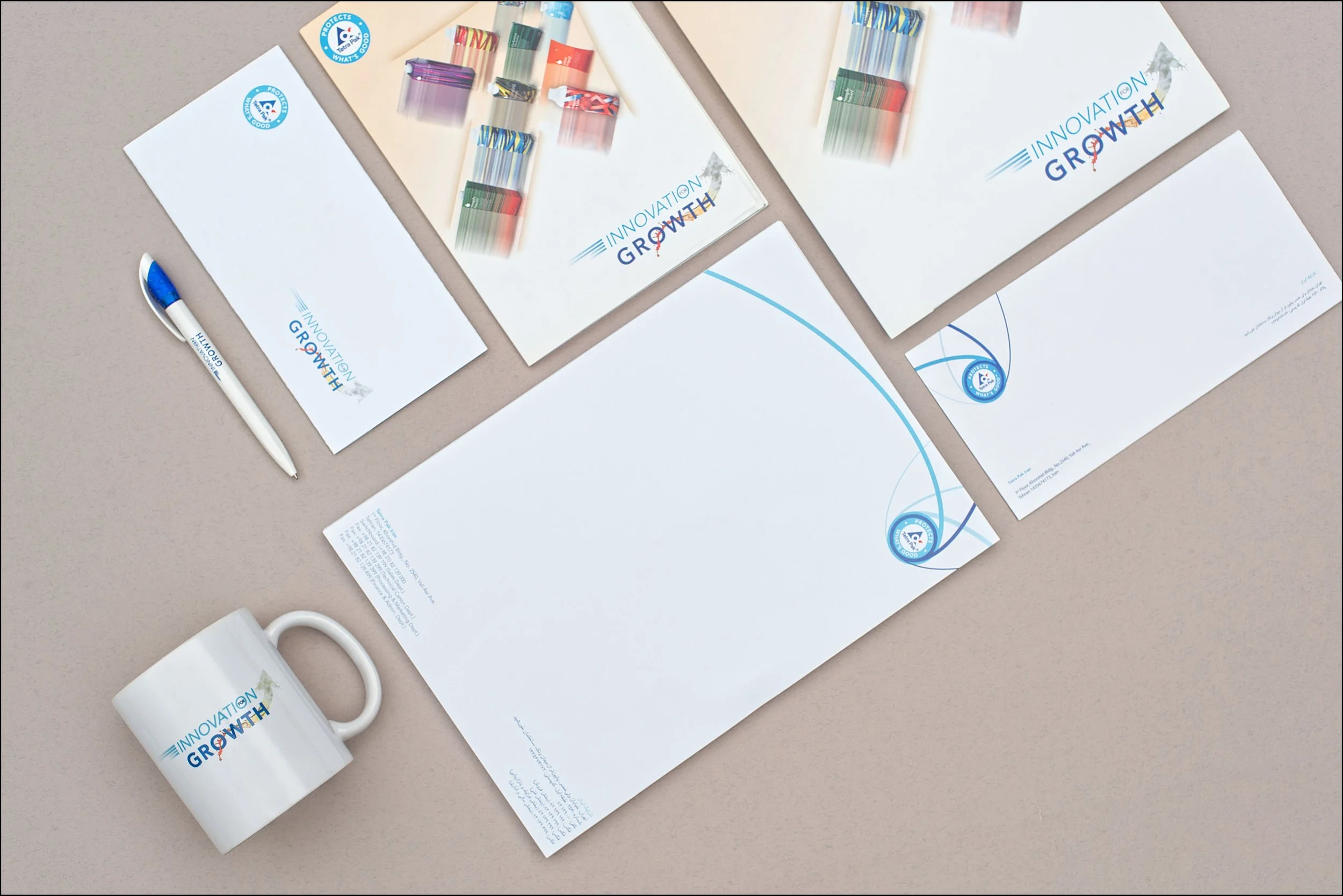 Arrangement of stationery items including a white mug, a pen, and papers and notebooks with 'Innovation Growth' branding on a beige surface.